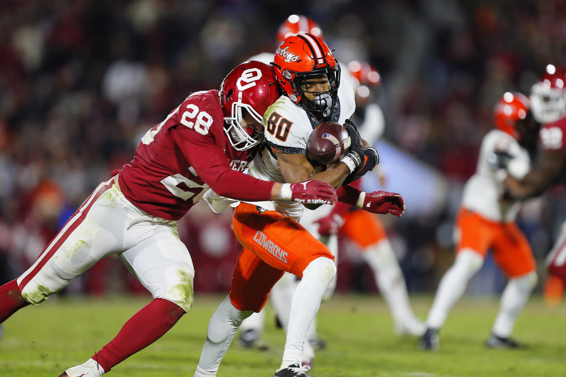 NORMAN, OK - NOVEMBER 19:  Wide receiver Brennan Presley #80 of the Oklahoma State Cowboys pulls down a pass for a 10-yard gain to the 16 as he is hit by linebacker Danny Stutsman #28 of the Oklahoma Sooners in the fourth quarter during Bedlam at Gaylord Family Oklahoma Memorial Stadium on November 19, 2022 in Norman, Oklahoma.  The Sooners won 28-13.  (Photo by Brian Bahr/Getty Images)