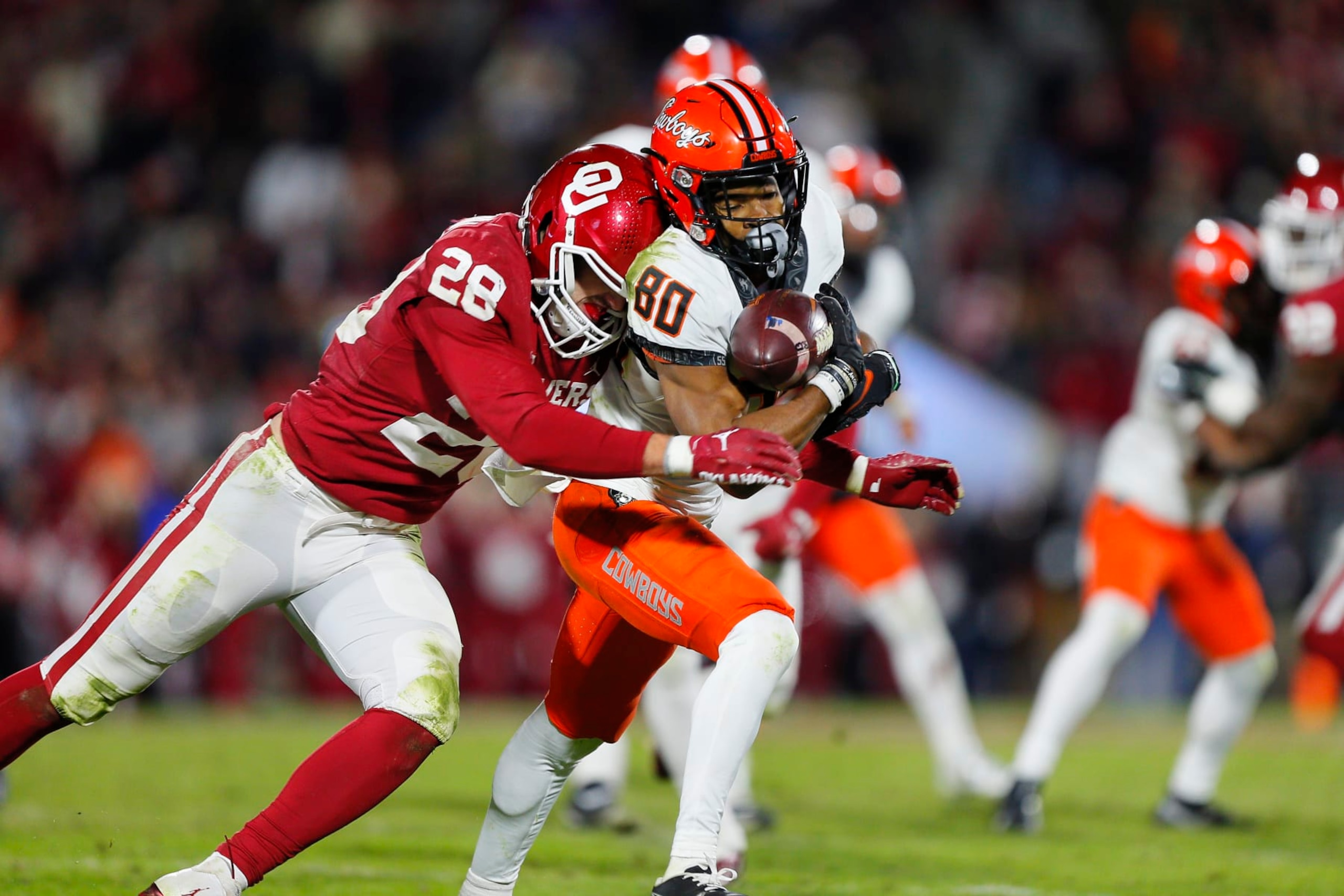 NORMAN, OK - NOVEMBER 19:  Wide receiver Brennan Presley #80 of the Oklahoma State Cowboys pulls down a pass for a 10-yard gain to the 16 as he is hit by linebacker Danny Stutsman #28 of the Oklahoma Sooners in the fourth quarter during Bedlam at Gaylord Family Oklahoma Memorial Stadium on November 19, 2022 in Norman, Oklahoma.  The Sooners won 28-13.  (Photo by Brian Bahr/Getty Images)