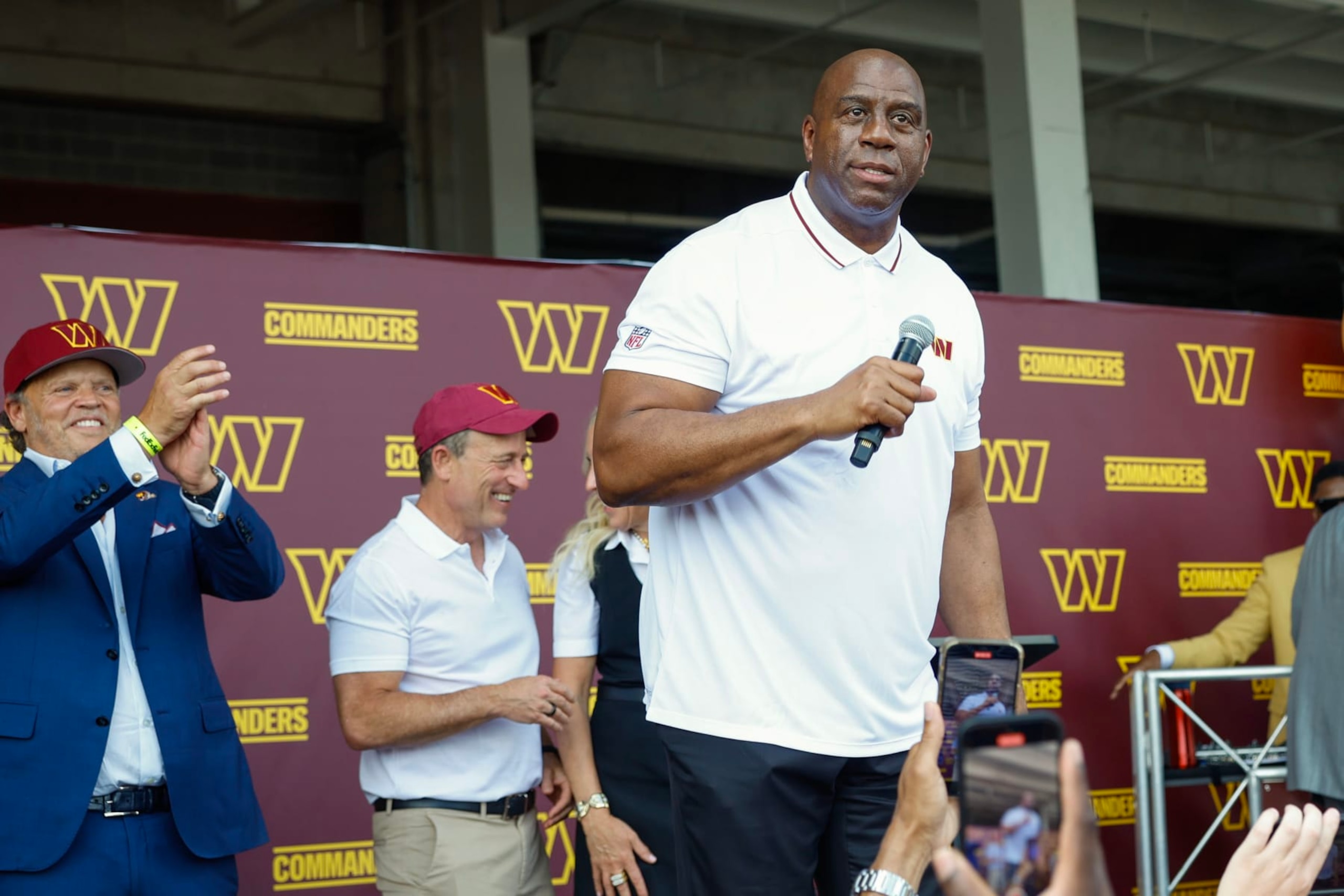 LANDOVER, MARYLAND - JULY 21: Earvin 'Magic' Johnson, a new owner of the Washington Commanders, greets fans at a pep rally after a press conference introducing the team's new ownership at on July 21, 2023 in Landover, Maryland. NFL teams owners have unanimously approved a $6.05 billion sale of the Commanders from Dan Snyder to a group led by Josh Harris. (Photo by Tasos Katopodis/Getty Images) LANDOVER, MARYLAND - JULY 21: Earvin 'Magic' Johnson, a new owner of the Washington Commanders, greets fans at a pep rally after a press conference introducing the team's new ownership at on July 21, 2023 in Landover, Maryland. NFL teams owners have unanimously approved a $6.05 billion sale of the Commanders from Dan Snyder to a group led by Josh Harris. (Photo by Tasos Katopodis/Getty Images)