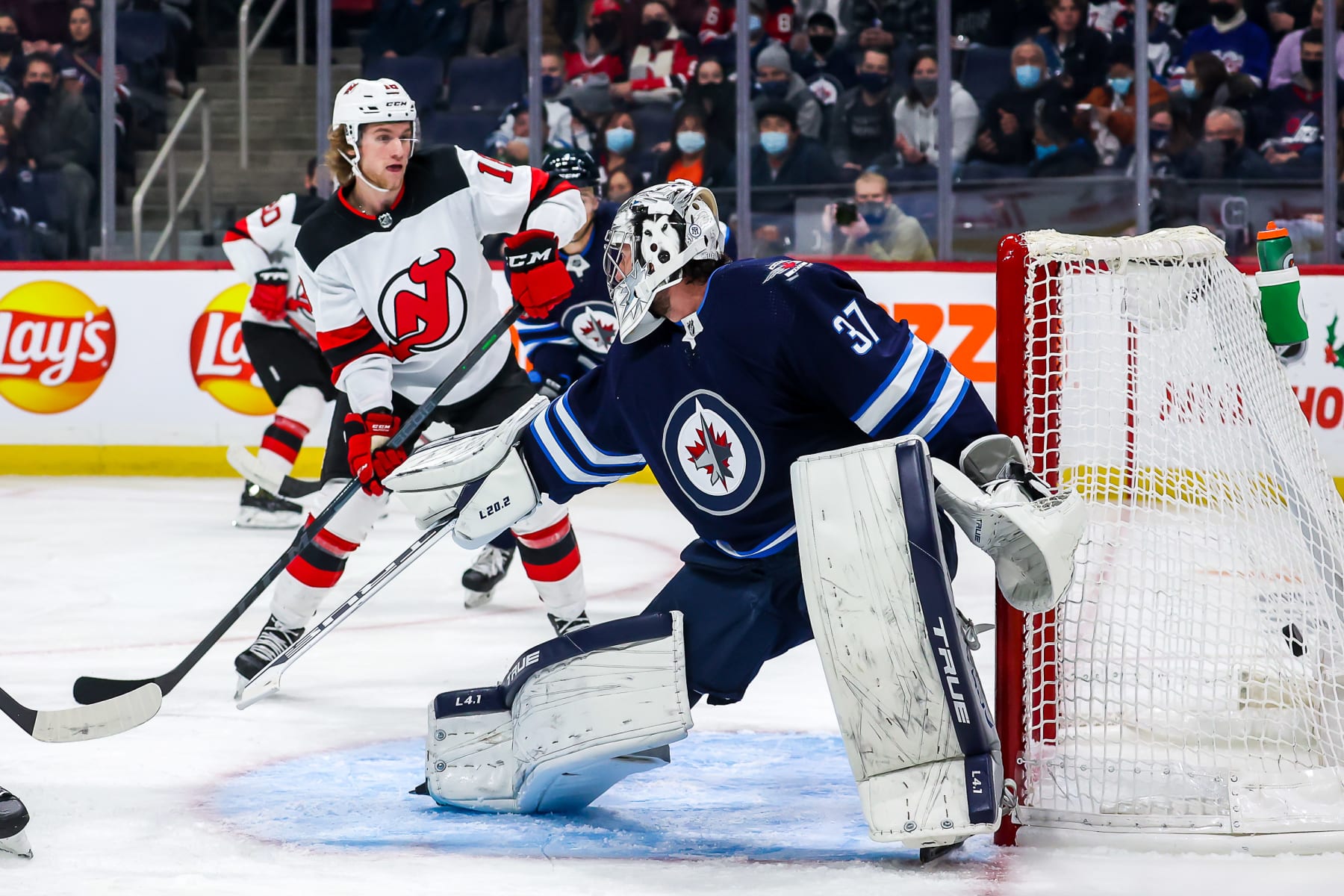 WINNIPEG, MB - DECEMBER 3: Dawson Mercer #18 of the New Jersey Devils looks on as the puck gets behind goaltender Connor Hellebuyck #37 of the Winnipeg Jets for a first period goal at the Canada Life Centre on December 3, 2021 in Winnipeg, Manitoba, Canada. (Photo by Jonathan Kozub/NHLI via Getty Images)