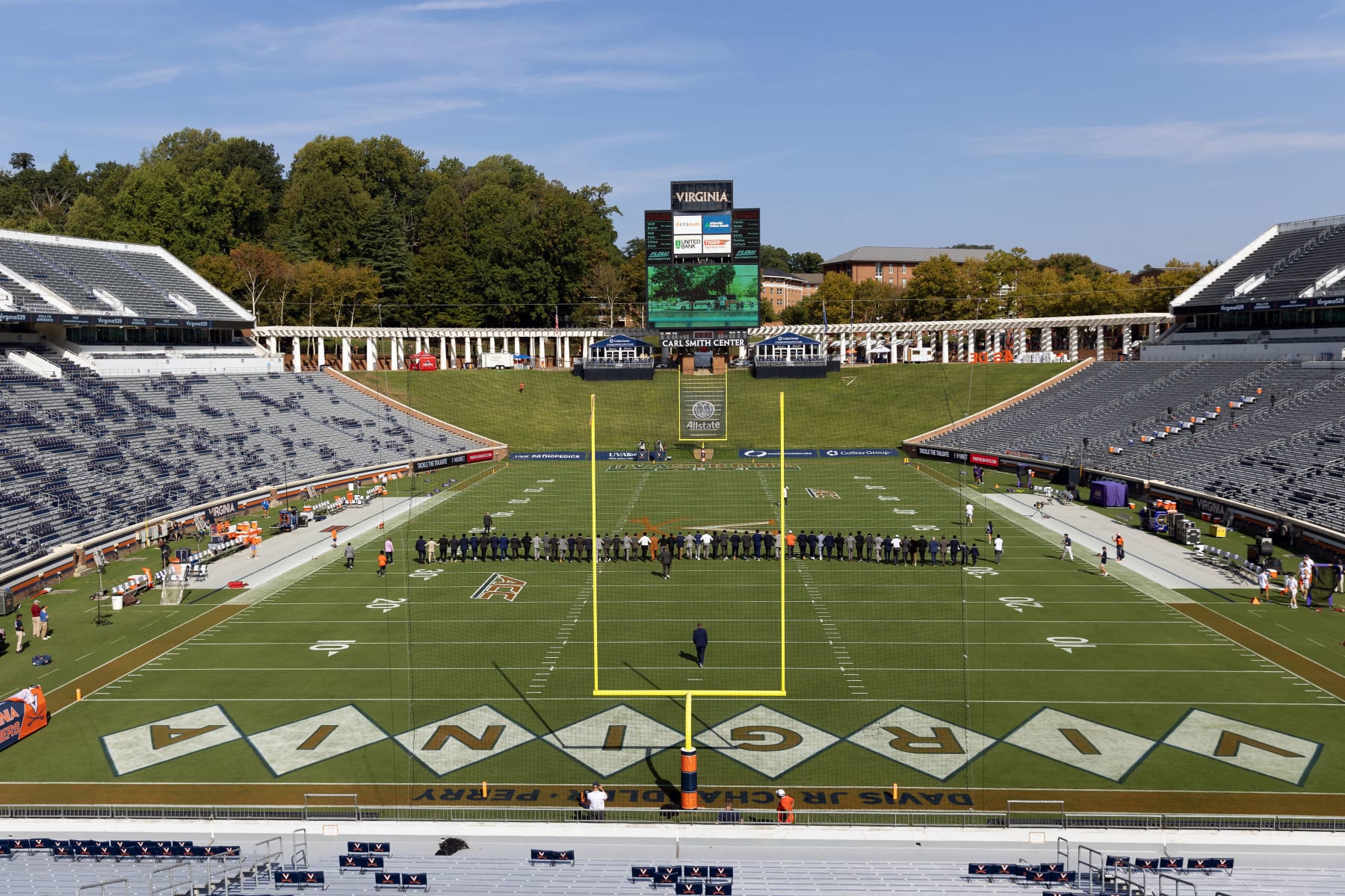 CHARLOTTESVILLE, VIRGINIA - SEPTEMBER 9: Virginia Cavaliers teammates walk arm in arm across the field before the start of a game against the James Madison Dukes at Scott Stadium on September 9, 2023 in Charlottesville, Virginia. Pregame ceremonies honored teammates D'Sean Perry, Devin Chandler and Lavel Davis Jr., who were killed during a shooting last year. (Photo by Ryan M. Kelly/Getty Images)