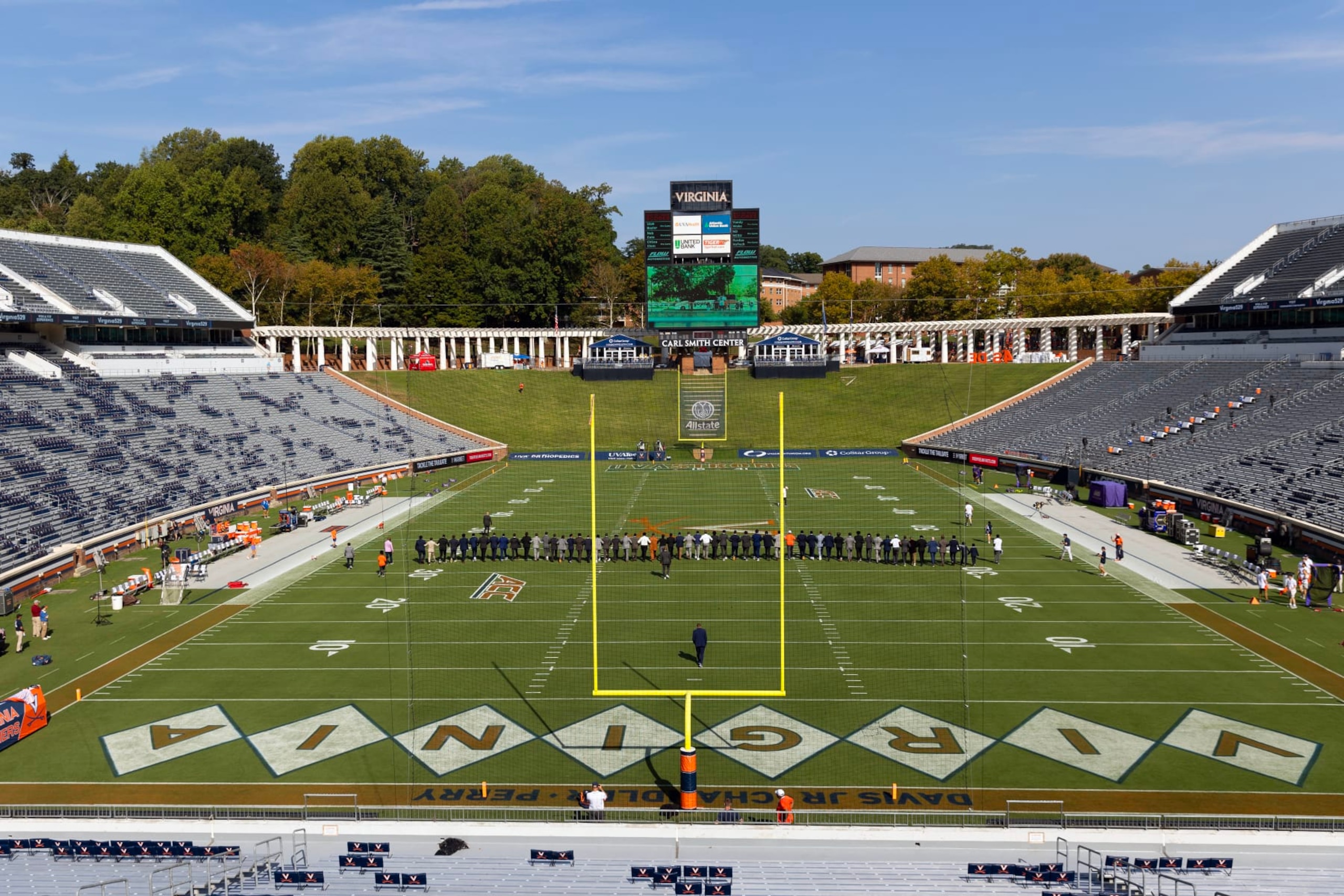CHARLOTTESVILLE, VIRGINIA - SEPTEMBER 9: Virginia Cavaliers teammates walk arm in arm across the field before the start of a game against the James Madison Dukes at Scott Stadium on September 9, 2023 in Charlottesville, Virginia. Pregame ceremonies honored teammates D'Sean Perry, Devin Chandler and Lavel Davis Jr., who were killed during a shooting last year. (Photo by Ryan M. Kelly/Getty Images)