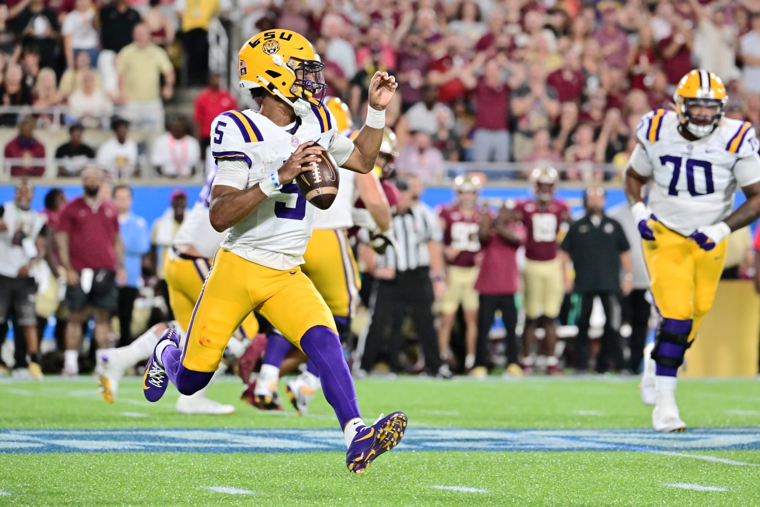 ORLANDO, FLORIDA - SEPTEMBER 03: Jayden Daniels #5 of the LSU Tigers scrambles with the ball in the first quarter against the Florida State Seminoles at Camping World Stadium on September 03, 2023 in Orlando, Florida. (Photo by Julio Aguilar/Getty Images)