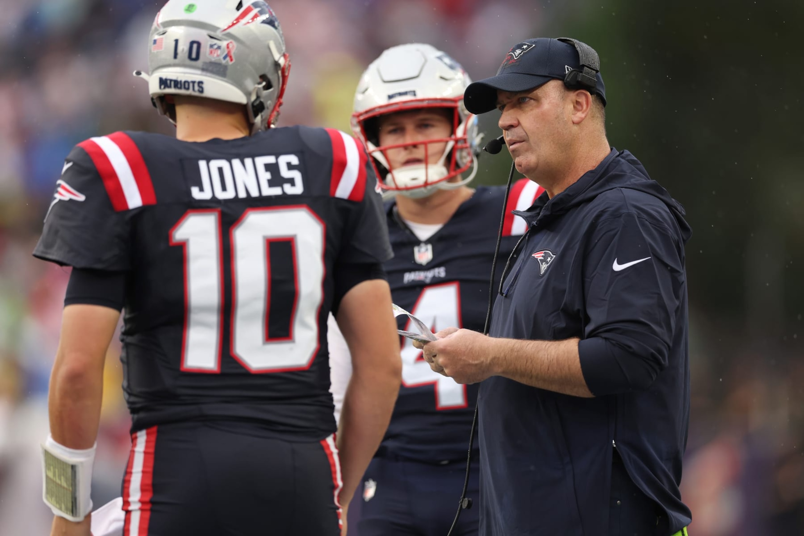 FOXBOROUGH, MASSACHUSETTS - SEPTEMBER 10: Bailey Zappe #4 of the New England Patriots watches offensive coordinator Bill O'Brien of the New England Patriots talks to Mac Jones #10 of the New England Patriots during the second quarter against the Philadelphia Eagles at Gillette Stadium on September 10, 2023 in Foxborough, Massachusetts. (Photo by Maddie Meyer/Getty Images)