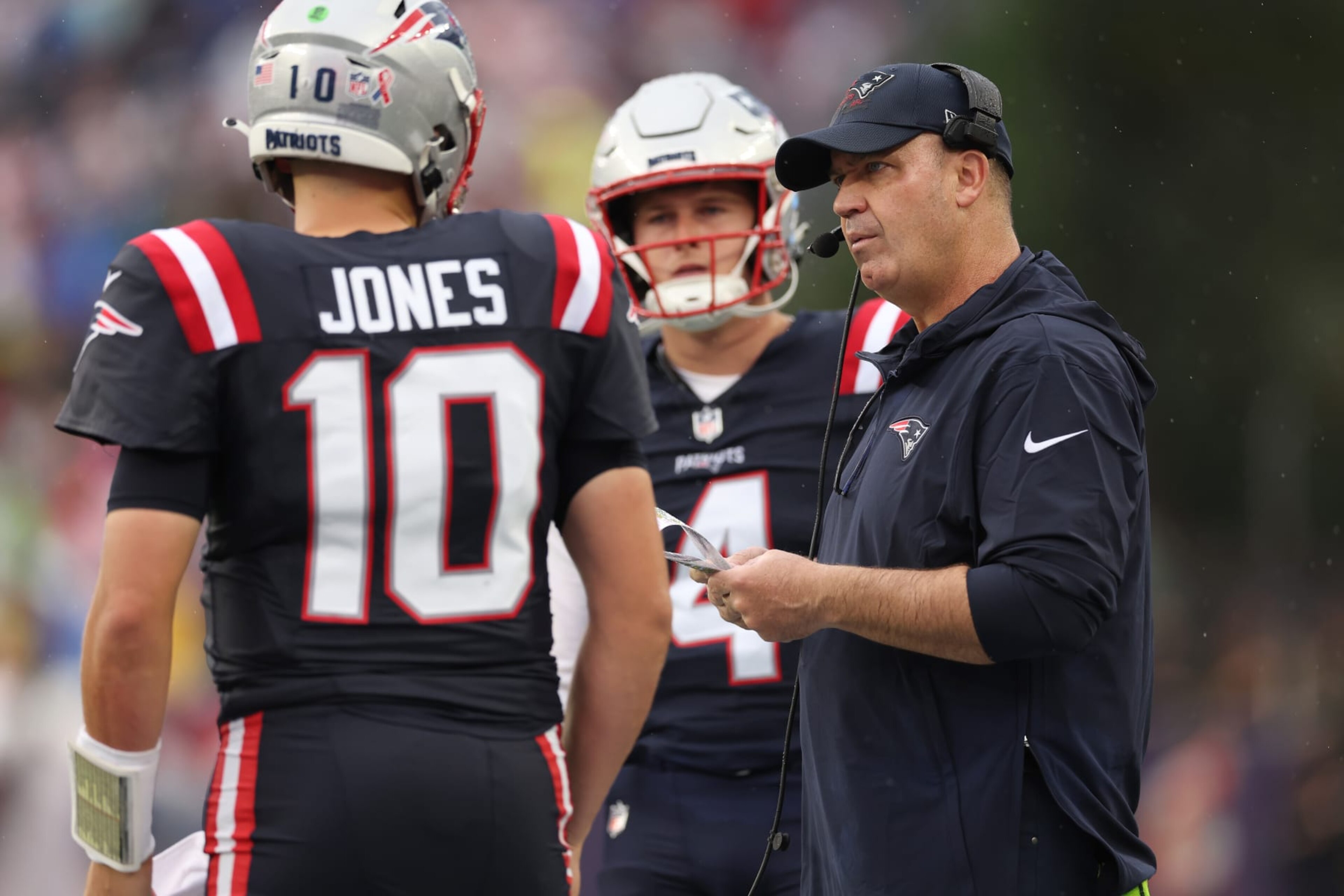FOXBOROUGH, MASSACHUSETTS - SEPTEMBER 10: Bailey Zappe #4 of the New England Patriots watches offensive coordinator Bill O'Brien of the New England Patriots talks to Mac Jones #10 of the New England Patriots during the second quarter against the Philadelphia Eagles at Gillette Stadium on September 10, 2023 in Foxborough, Massachusetts. (Photo by Maddie Meyer/Getty Images)