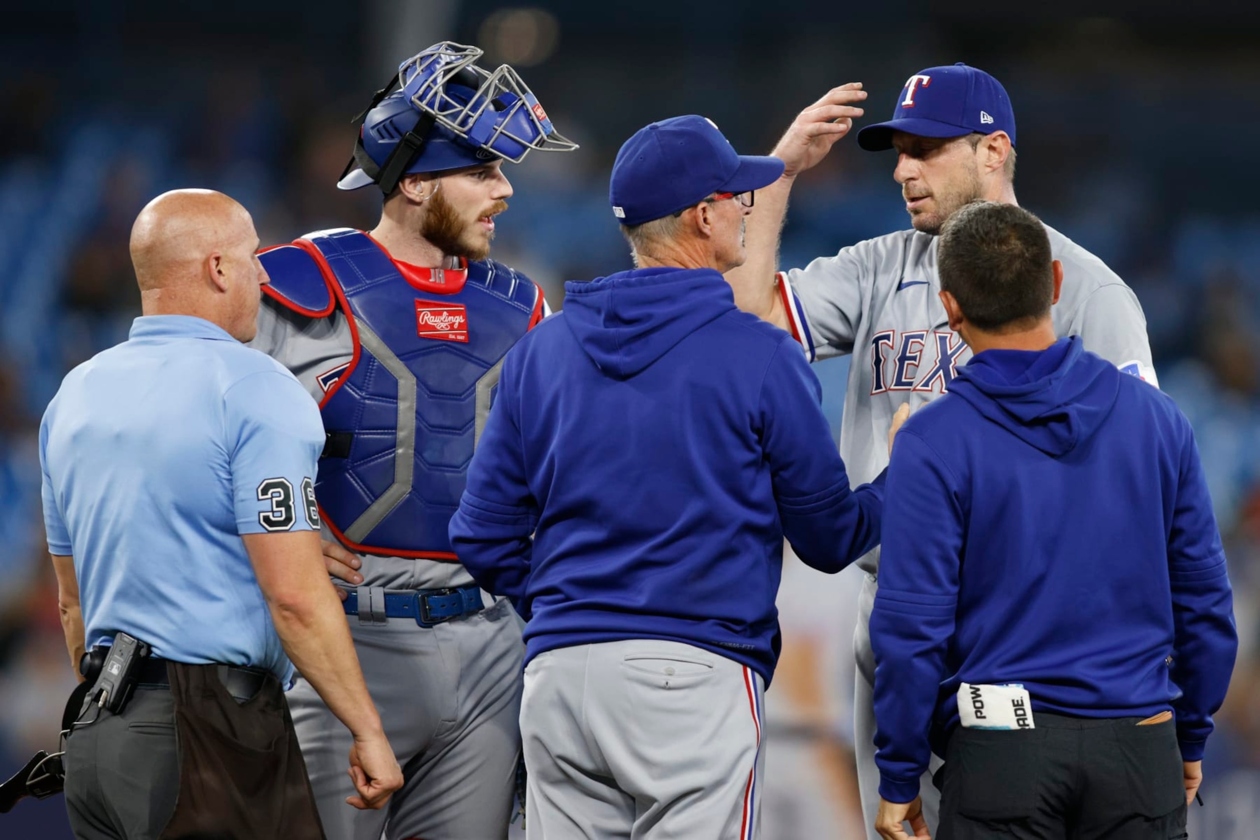 TORONTO, CANADA - SEPTEMBER 12: Max Scherzer #31 of the Texas Rangers meets with trainers and coaches on the mound before leaving the game in the sixth inning against the Toronto Blue Jays at Rogers Centre on September 12, 2023 in Toronto, Canada. (Photo by Cole Burston/Getty Images)