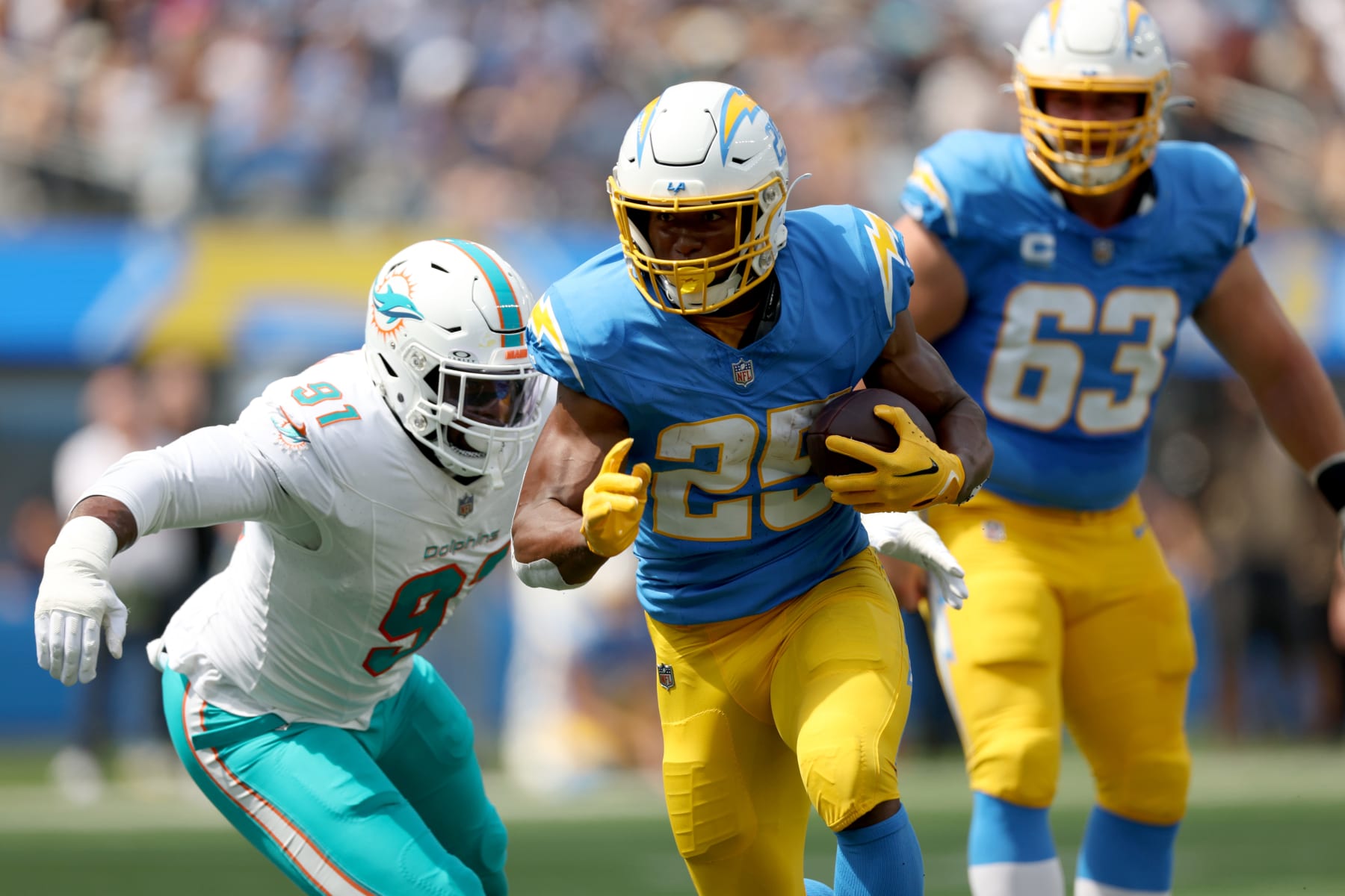 INGLEWOOD, CALIFORNIA - SEPTEMBER 10: Joshua Kelley #25 of the Los Angeles Chargers carries the ball past Emmanuel Ogbah #91 of the Miami Dolphins during a 36-34 loss to the Miami Dolphins at SoFi Stadium on September 10, 2023 in Inglewood, California. (Photo by Harry How/Getty Images)
