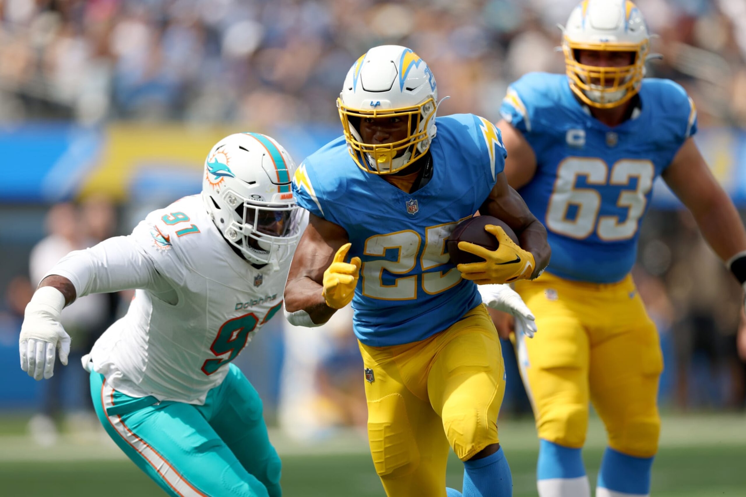 INGLEWOOD, CALIFORNIA - SEPTEMBER 10: Joshua Kelley #25 of the Los Angeles Chargers carries the ball past Emmanuel Ogbah #91 of the Miami Dolphins during a 36-34 loss to the Miami Dolphins at SoFi Stadium on September 10, 2023 in Inglewood, California. (Photo by Harry How/Getty Images)