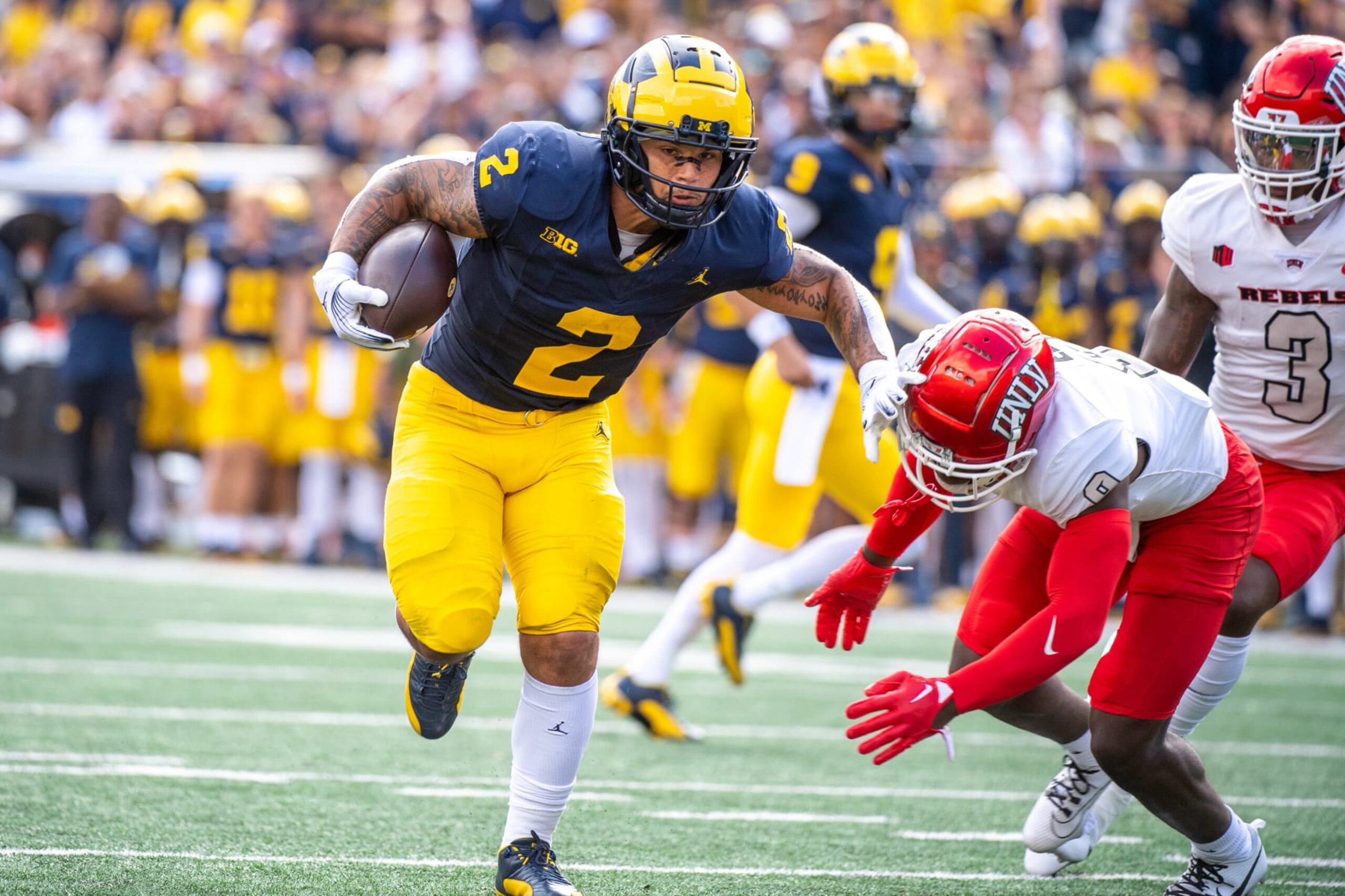 ANN ARBOR, MICHIGAN - SEPTEMBER 09: Blake Corum #2 of the Michigan Wolverines runs for extra yardage against Jett Elad #9 of the UNLV Rebels during the first half of a college football game at Michigan Stadium on September 09, 2023 in Ann Arbor, Michigan. (Photo by Aaron J. Thornton/Getty Images) ANN ARBOR, MICHIGAN - SEPTEMBER 09: Blake Corum #2 of the Michigan Wolverines runs for extra yardage against Jett Elad #9 of the UNLV Rebels during the first half of a college football game at Michigan Stadium on September 09, 2023 in Ann Arbor, Michigan. (Photo by Aaron J. Thornton/Getty Images)