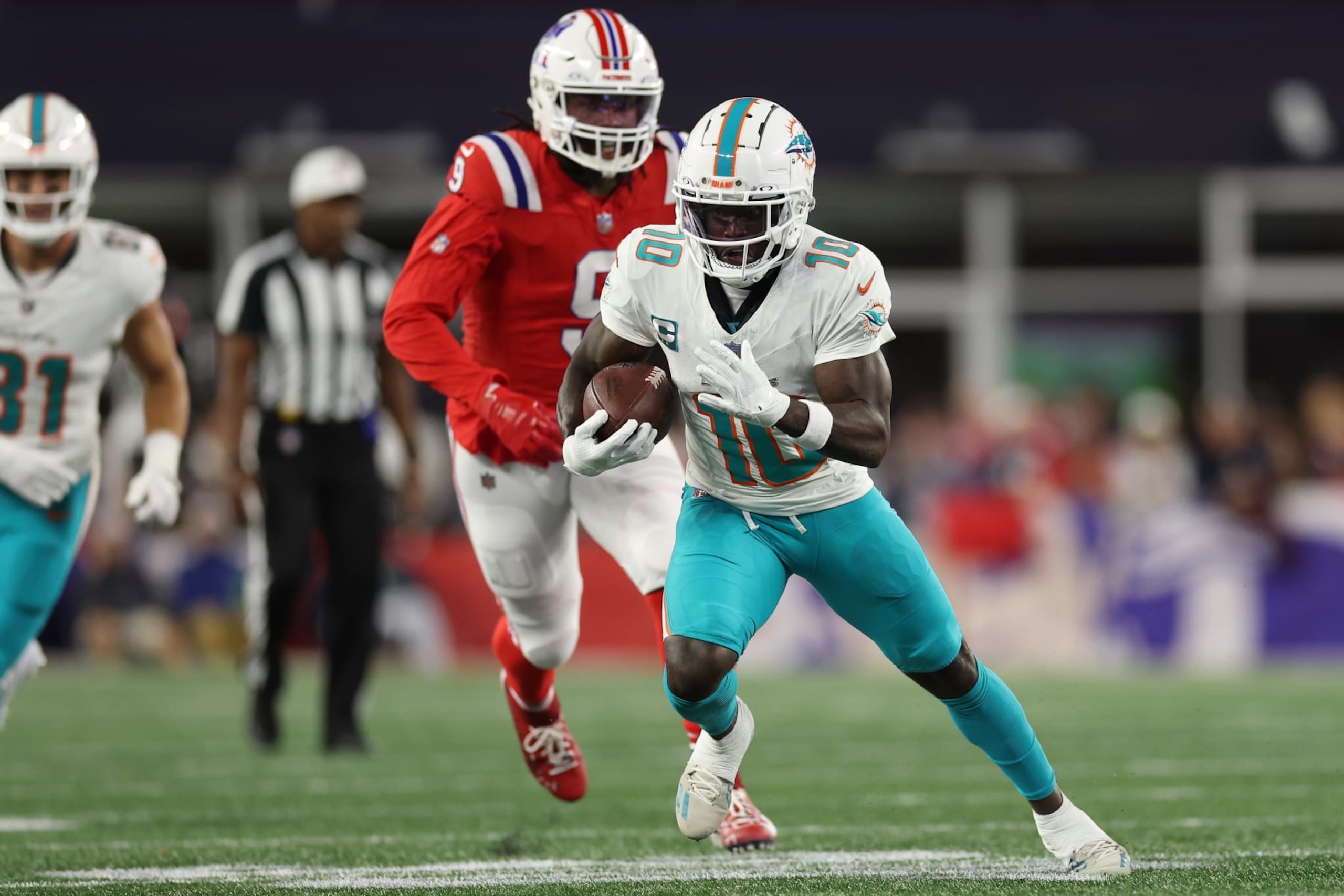 FOXBOROUGH, MASSACHUSETTS - SEPTEMBER 17: Tyreek Hill #10 of the Miami Dolphins runs the ball ahead of Matthew Judon #9 of the New England Patriots during the first quarter at Gillette Stadium on September 17, 2023 in Foxborough, Massachusetts. (Photo by Maddie Meyer/Getty Images)