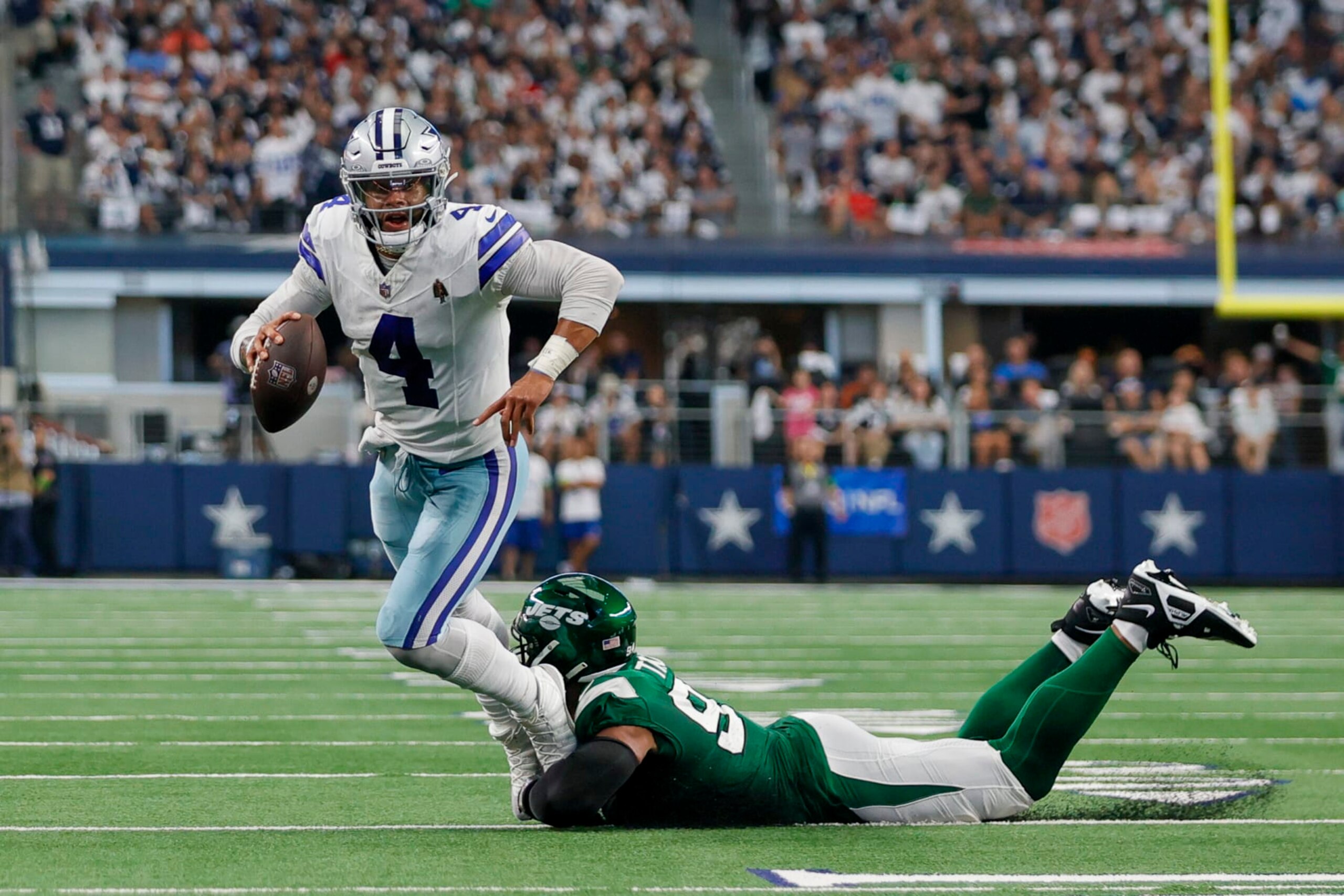 ARLINGTON, TX - SEPTEMBER 17: Dallas Cowboys quarterback Dak Prescott (4) gets tripped up by New York Jets defensive end Solomon Thomas (94) during the game between the Dallas Cowboys and the New York Jets on September 17, 2023 at AT&T Stadium in Arlington, Texas. (Photo by Matthew Pearce/Icon Sportswire via Getty Images)