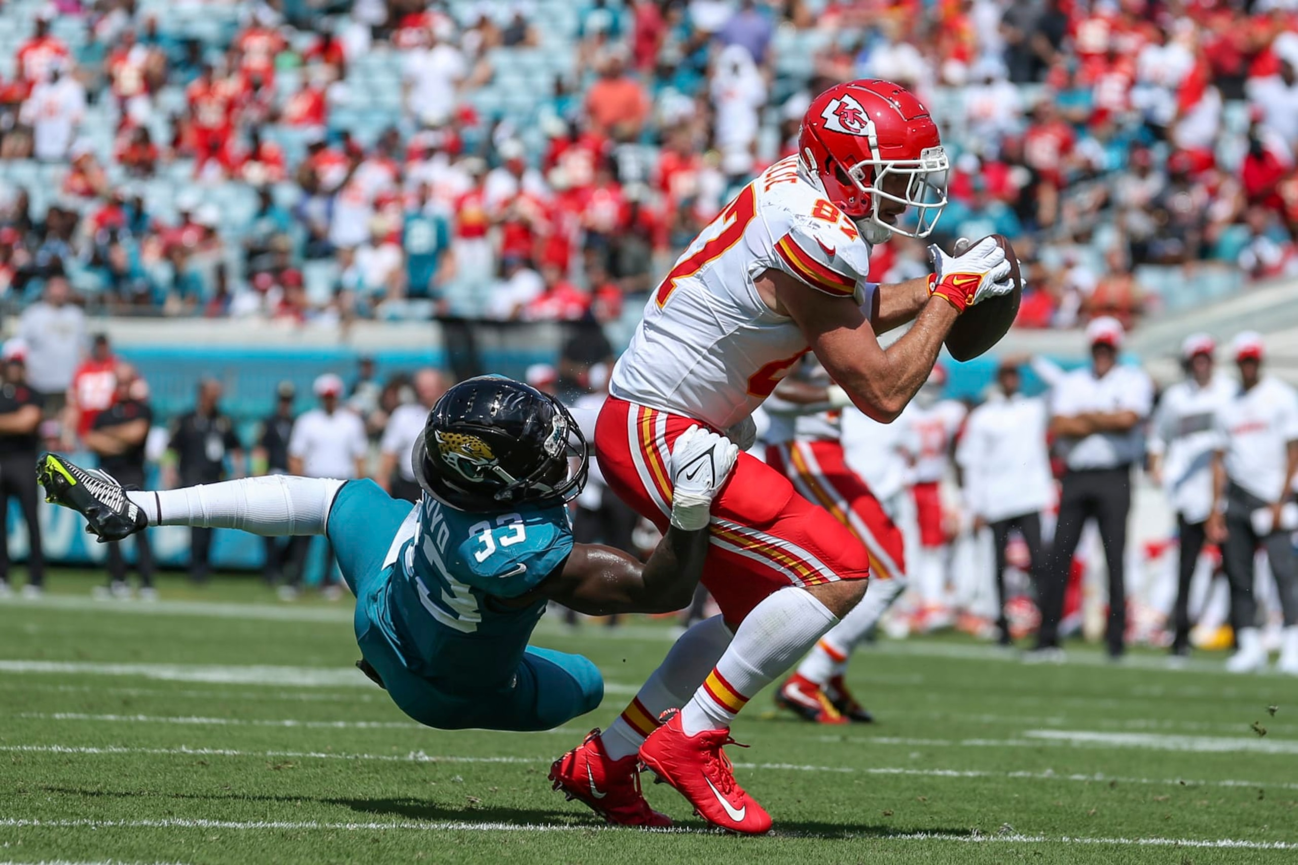 Kansas City Chiefs tight end Travis Kelce (87) catches a pass while defended by Jacksonville Jaguars linebacker Devin Lloyd (33), left, in action during the second half of an NFL football game, Sunday, Sept. 17, 2023, in Jacksonville, Fla. The Chiefs defeated the Jaguars 17-9. (AP Photo/Gary McCullough)