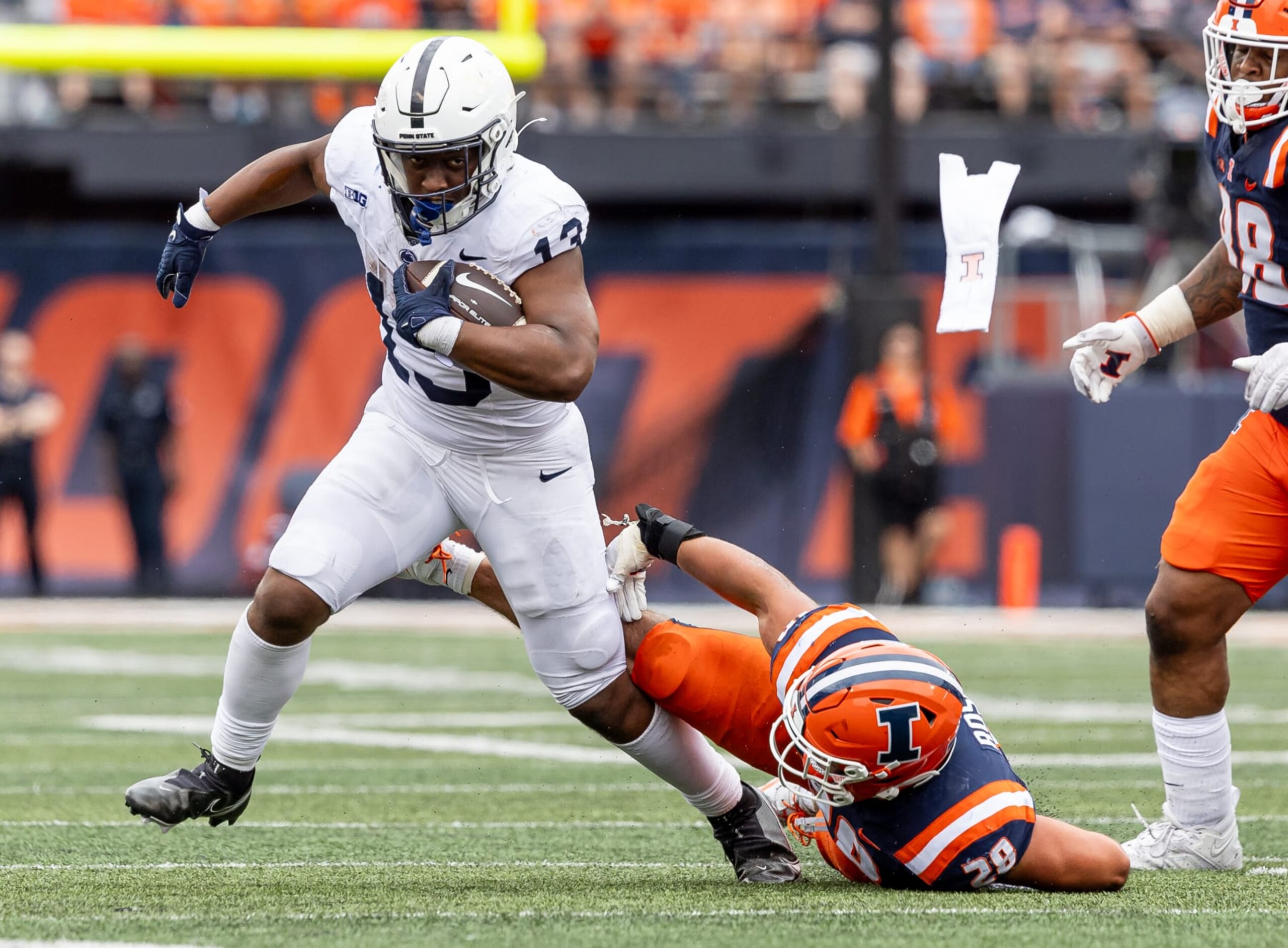 CHAMPAIGN, ILLINOIS - SEPTEMBER 16: Kaytron Allen #13 of the Penn State Nittany Lions runs the ball as Dylan Rosiek #28 of the Illinois Fighting Illini reaches for the tackle during the game at Memorial Stadium on September 16, 2023 in Champaign, Illinois. (Photo by Michael Hickey/Getty Images)
