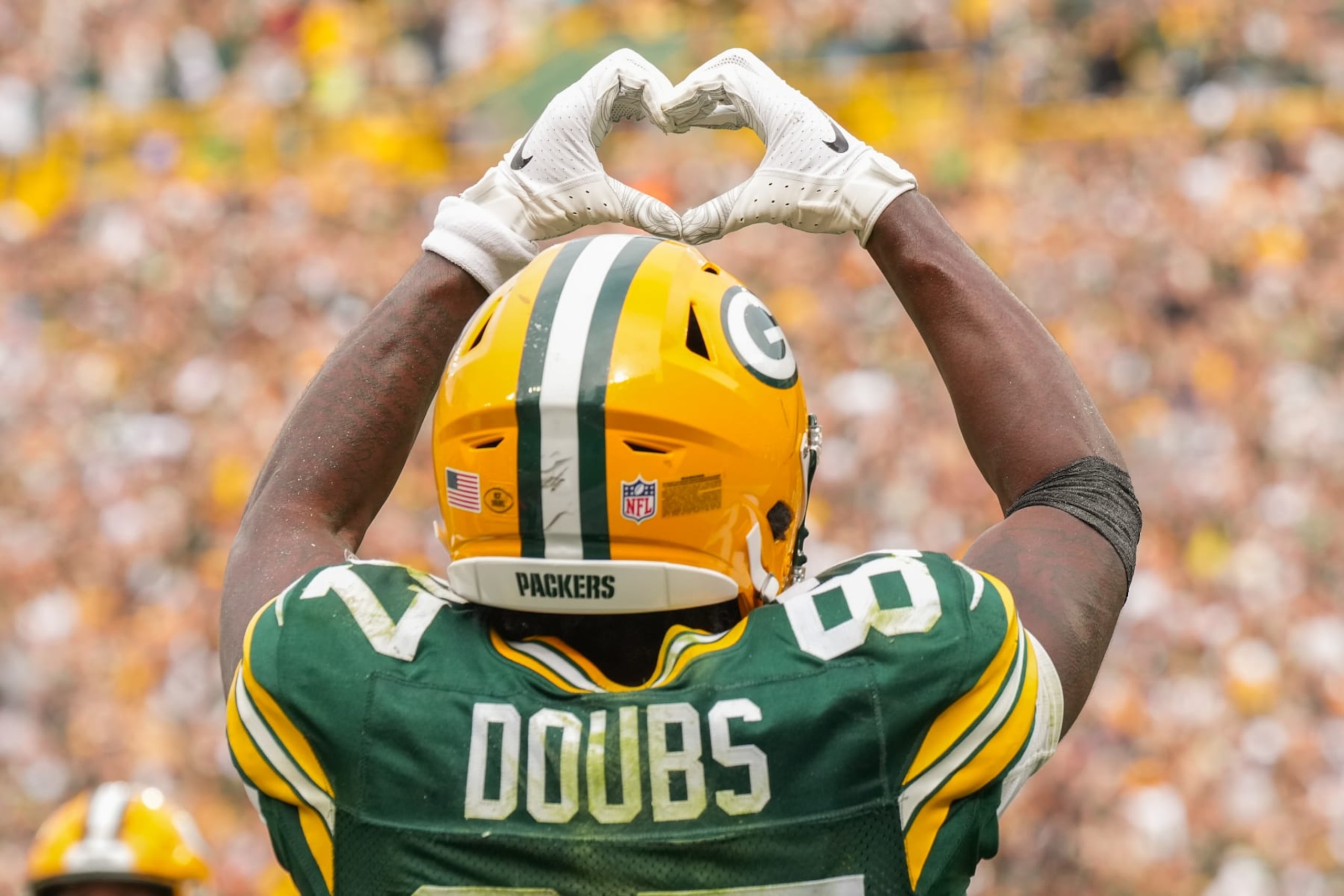 GREEN BAY, WI - SEPTEMBER 24: Romeo Doubs #87 of the Green Bay Packers celebrates a touchdown with the Love symbol during the second half of an NFL football game against the New Orleans Saints at Lambeau Field on September 24, 2023 in Green Bay, Wisconsin. The Packers beat the Saints 18-17. (Photo by Todd Rosenberg/Getty Images)