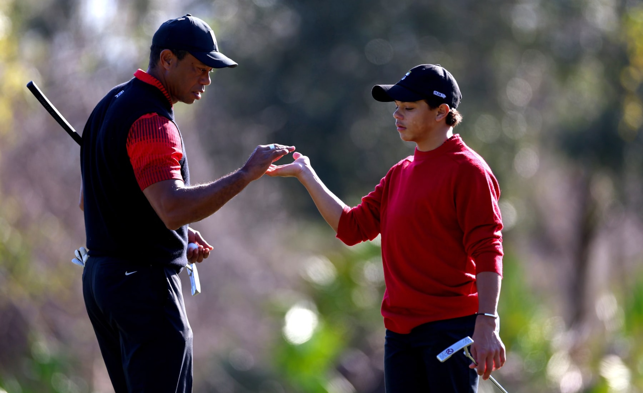 ORLANDO, FLORIDA - DECEMBER 18: Tiger Woods and Charlie Woods high five on the 1th hole during the final round of the PNC Championship at Ritz-Carlton Golf Club on December 18, 2022 in Orlando, Florida. (Photo by Mike Ehrmann/Getty Images)
