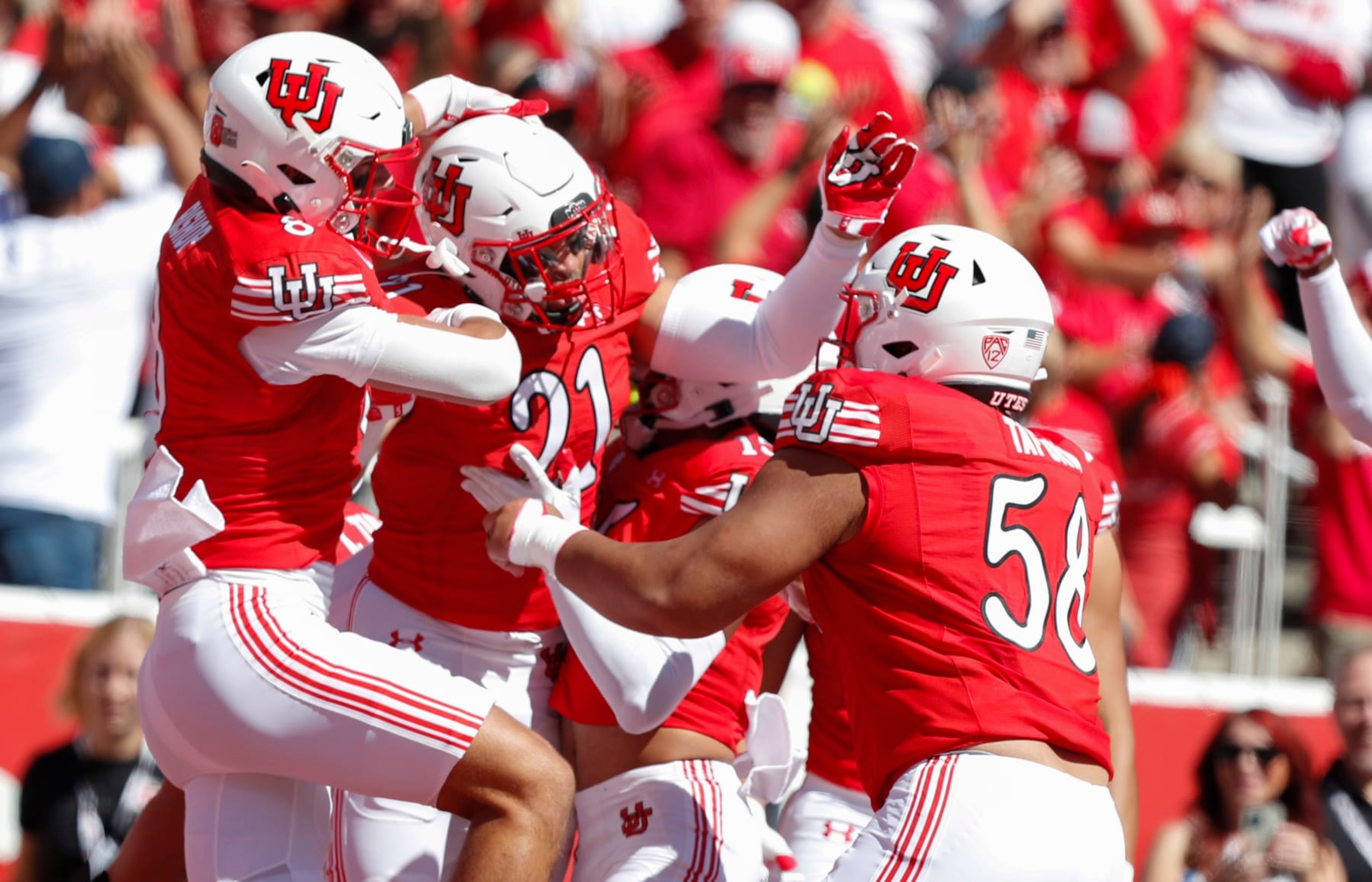 SALT LAKE CITY, UT - SEPTEMBER 23: Karene Reid #21 of the Utah Utes is congratulated by teammates Cole Bishop #8 and Junior Tafuna #58 after running back an interception for touchdown against the UCLA Bruins during the first half of their game at Rice-Eccles Stadium on September 23, 2023 in Salt Lake City, Utah. (Photo by Chris Gardner/Getty Images)