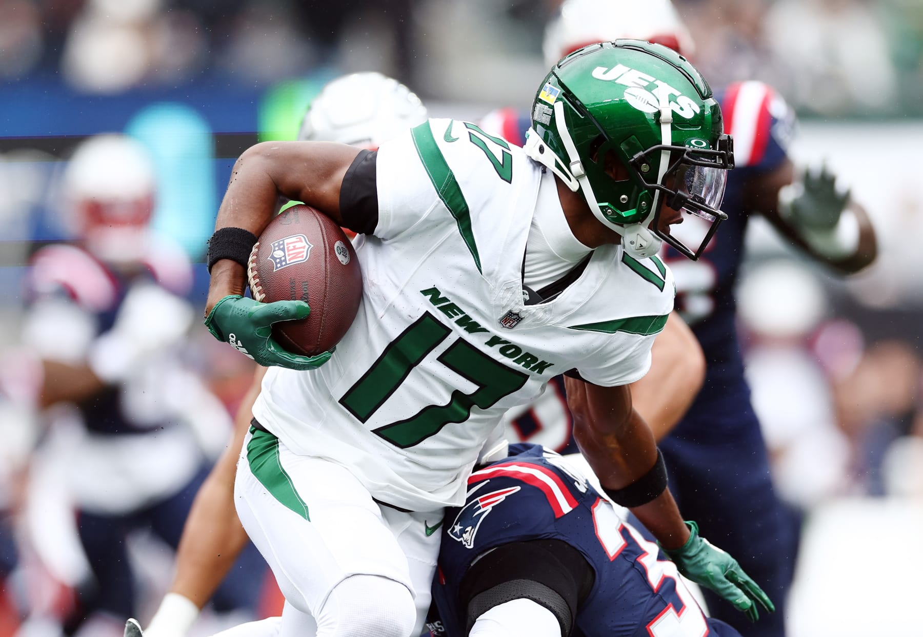 EAST RUTHERFORD, NEW JERSEY - SEPTEMBER 24: Garrett Wilson #17 of the New York Jets runs with the ball as Anfernee Jennings #33 of the New England Patriots comes in for a stop in the first quarter at MetLife Stadium on September 24, 2023 in East Rutherford, New Jersey. (Photo by Elsa/Getty Images)
