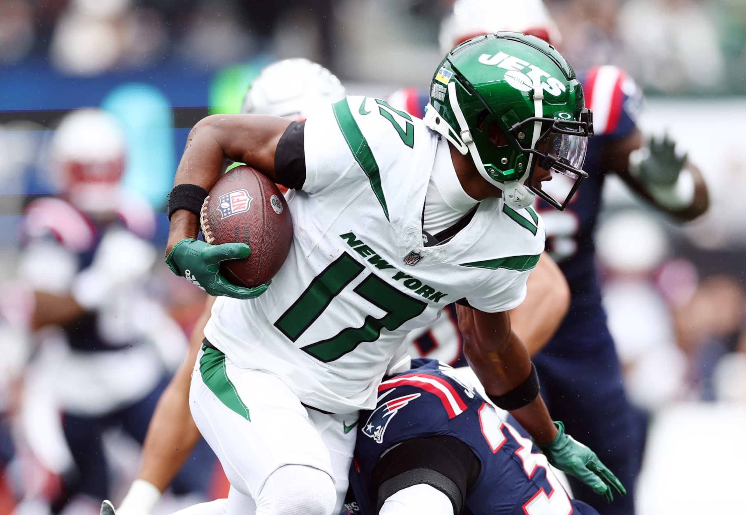 EAST RUTHERFORD, NEW JERSEY - SEPTEMBER 24: Garrett Wilson #17 of the New York Jets runs with the ball as Anfernee Jennings #33 of the New England Patriots comes in for a stop in the first quarter at MetLife Stadium on September 24, 2023 in East Rutherford, New Jersey. (Photo by Elsa/Getty Images)