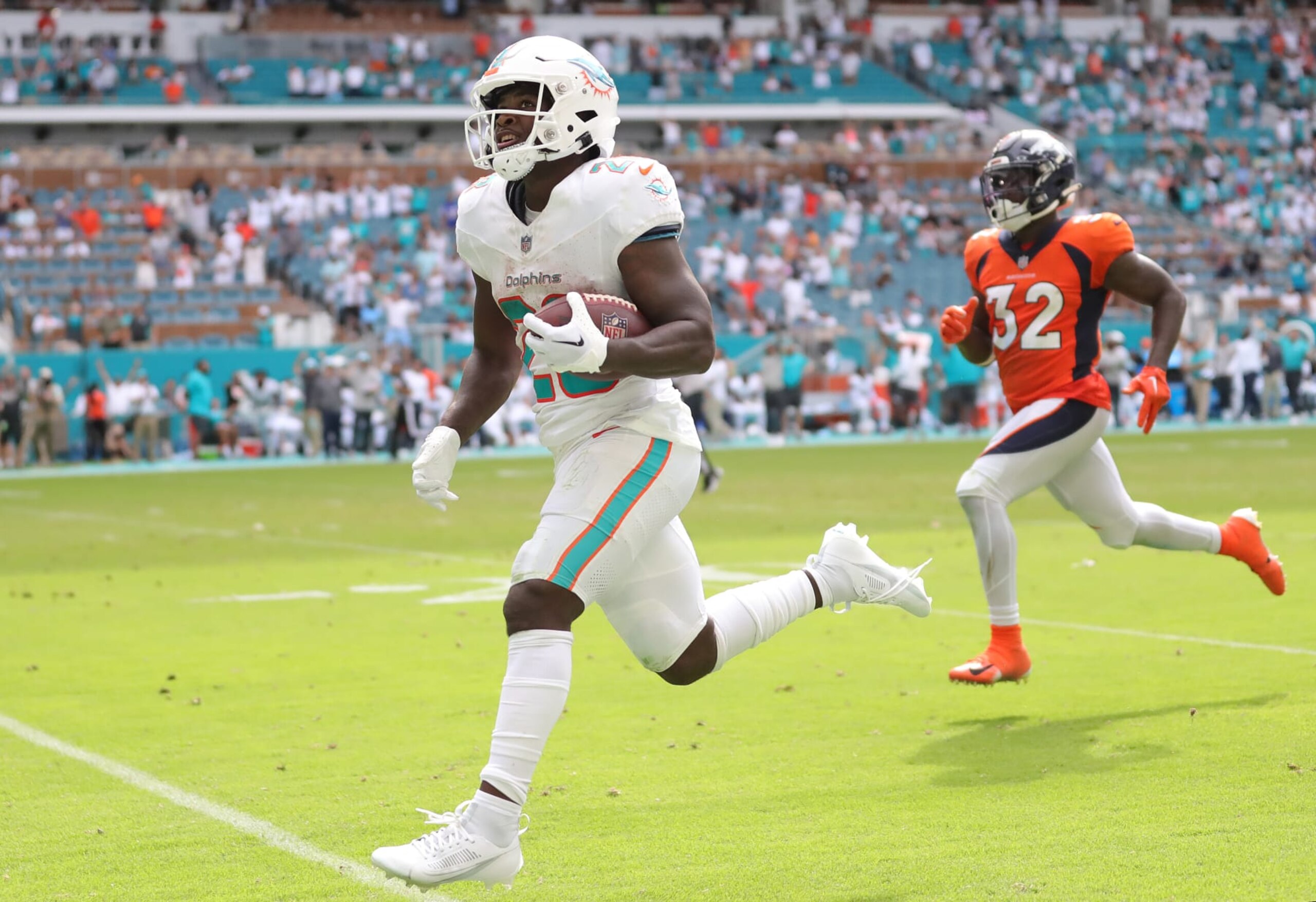 MIAMI GARDENS, FLORIDA - SEPTEMBER 24: De'Von Achane #28 of the Miami Dolphins runs past Delarrin Turner-Yell #32 of the Denver Broncos while scoring a rushing touchdown during the fourth quarter at Hard Rock Stadium on September 24, 2023 in Miami Gardens, Florida. (Photo by Megan Briggs/Getty Images)
