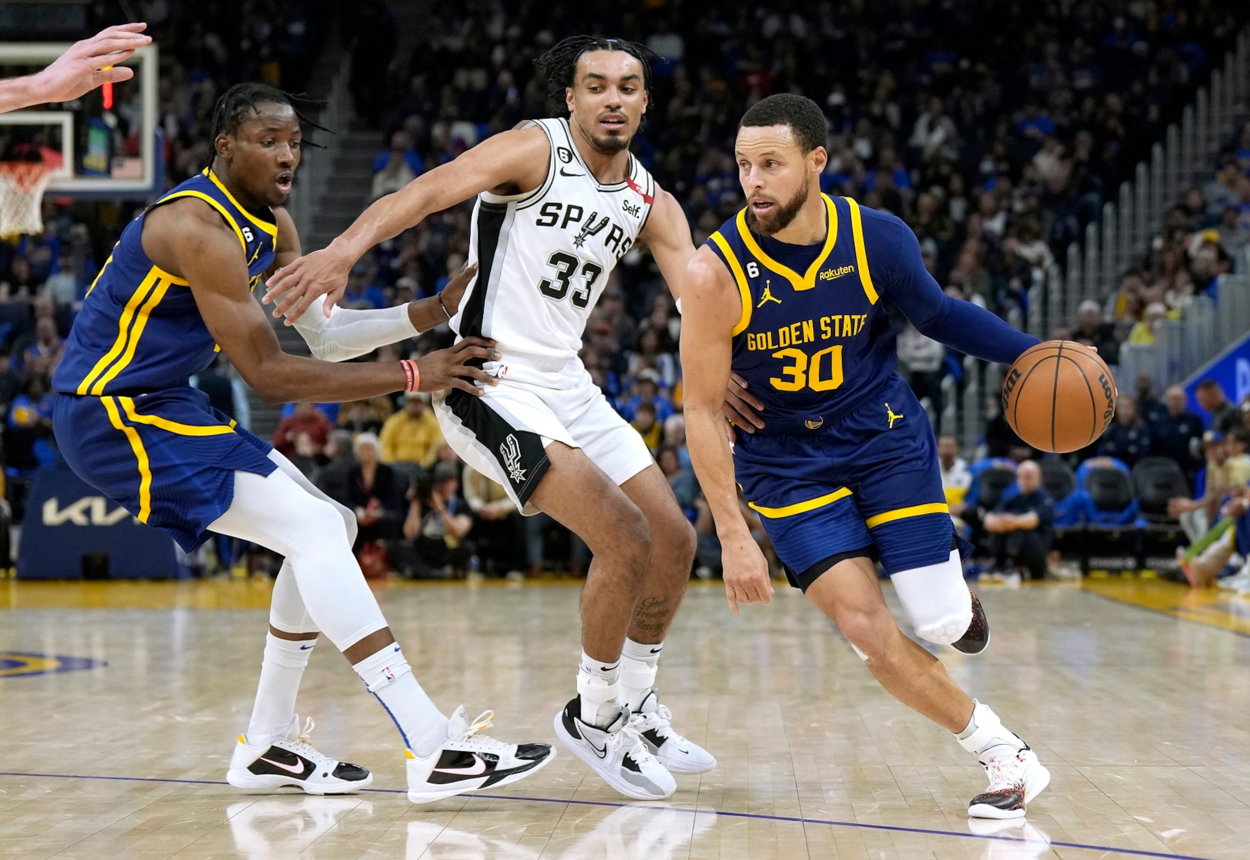 SAN FRANCISCO, CALIFORNIA - MARCH 31: Stephen Curry #30 of the Golden State Warriors dribbles around a screen set by Jonathan Kuminga #00 on Tre Jones #33 of the San Antonio Spurs during the third quarter at Chase Center on March 31, 2023 in San Francisco, California. NOTE TO USER: User expressly acknowledges and agrees that, by downloading and or using this photograph, User is consenting to the terms and conditions of the Getty Images License Agreement. (Photo by Thearon W. Henderson/Getty Images)