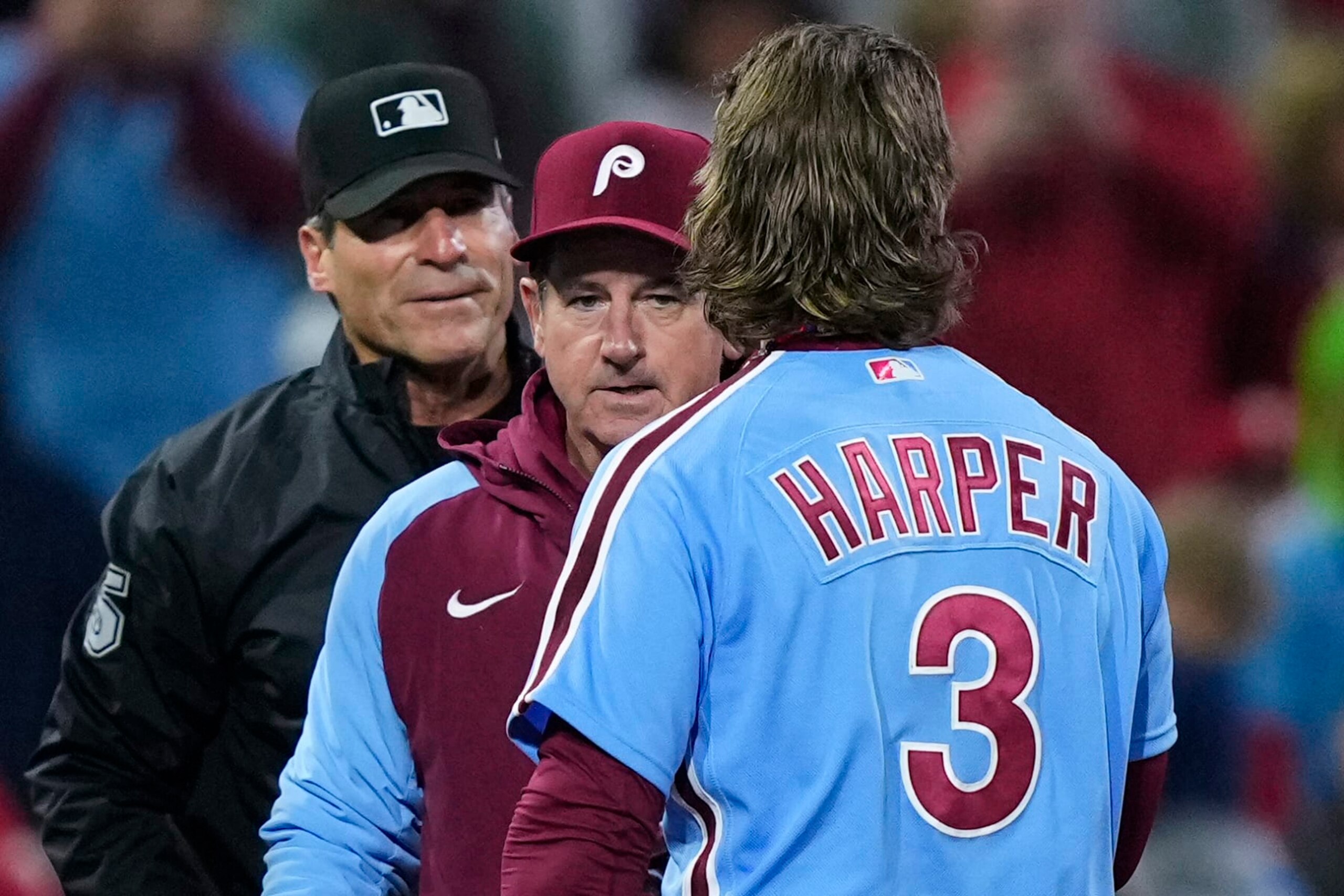 Philadelphia Phillies manager Rob Thomson, center, stands between Bryce Harper and umpire Ángel Hernández during the third inning of the team's baseball game against the Pittsburgh Pirates, Thursday, Sept. 28, 2023, in Philadelphia. Harper was ejected. (AP Photo/Matt Rourke)