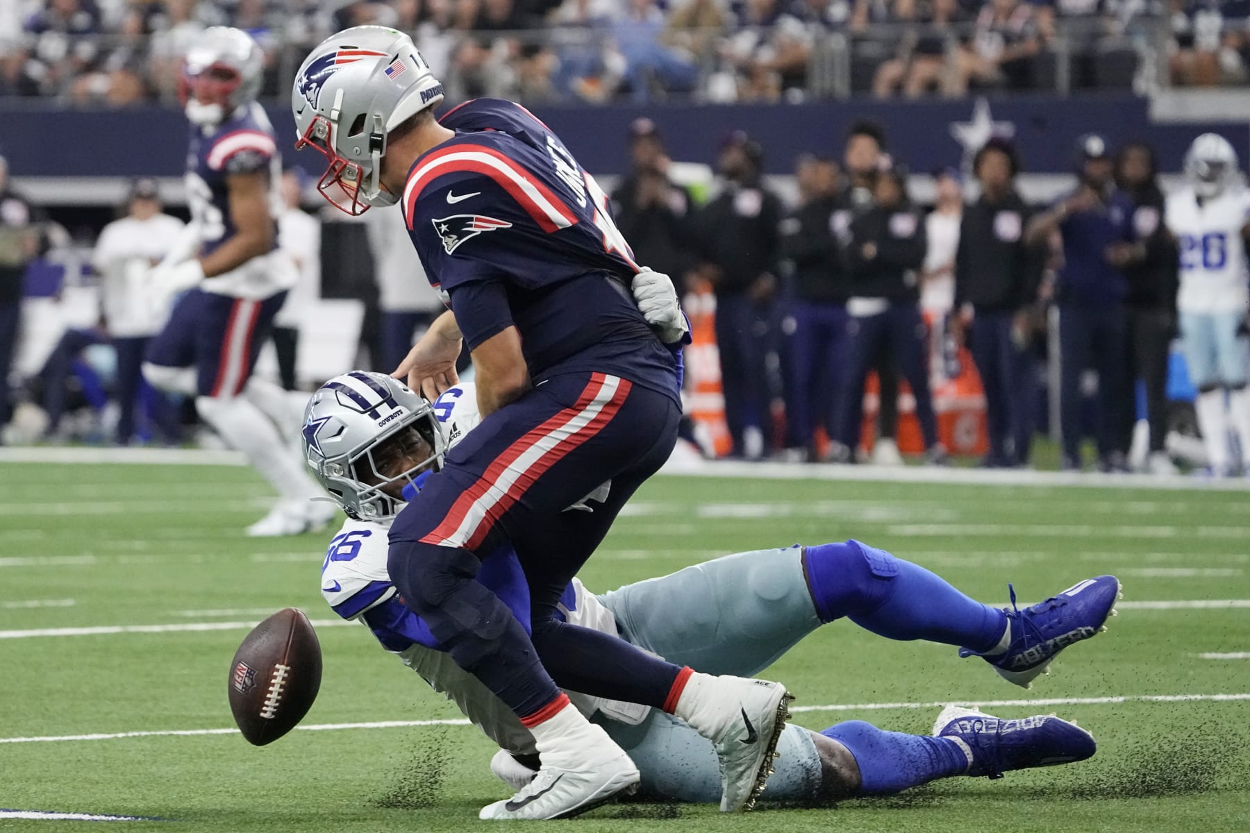 ARLINGTON, TEXAS - OCTOBER 01: Mac Jones #10 of the New England Patriots fumbles the ball while being tackled by Dante Fowler Jr. #56 of the Dallas Cowboys during the second quarter at AT&T Stadium on October 01, 2023 in Arlington, Texas. (Photo by Sam Hodde/Getty Images)