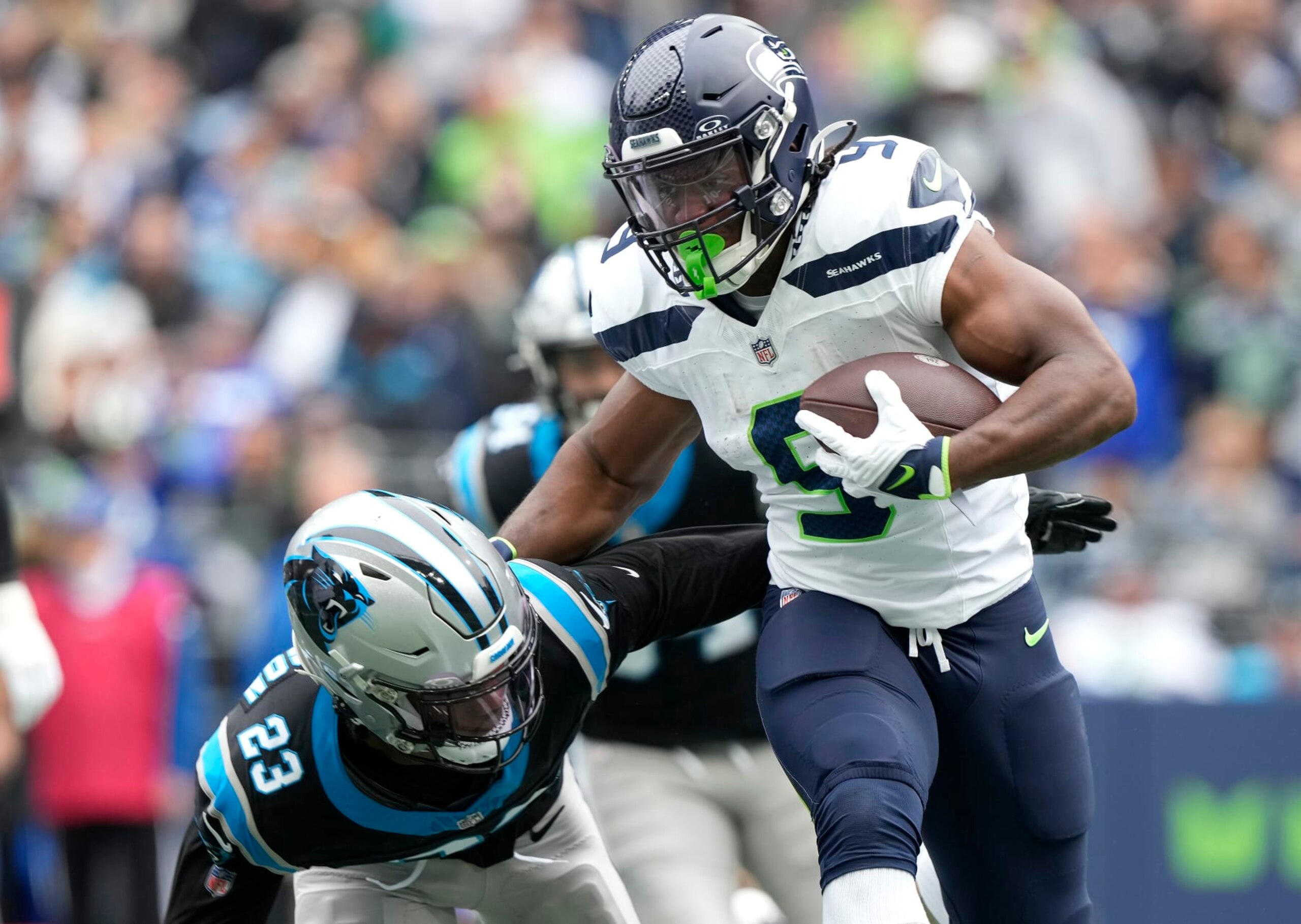 SEATTLE, WASHINGTON - SEPTEMBER 24: Kenneth Walker III #9 of the Seattle Seahawks stiff arms CJ Henderson #23 of the Carolina Panthers during the first quarter at Lumen Field on September 24, 2023 in Seattle, Washington. (Photo by Christopher Mast/Getty Images)