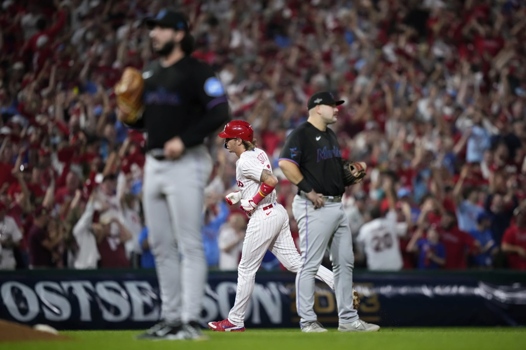 Philadelphia Phillies' Bryson Stott, center, rounds the bases after hitting a grand slam against Miami Marlins pitcher Andrew Nardi during the sixth inning of Game 2 in an NL wild-card baseball playoff series, Wednesday, Oct. 4, 2023, in Philadelphia. (AP Photo/Matt Slocum)