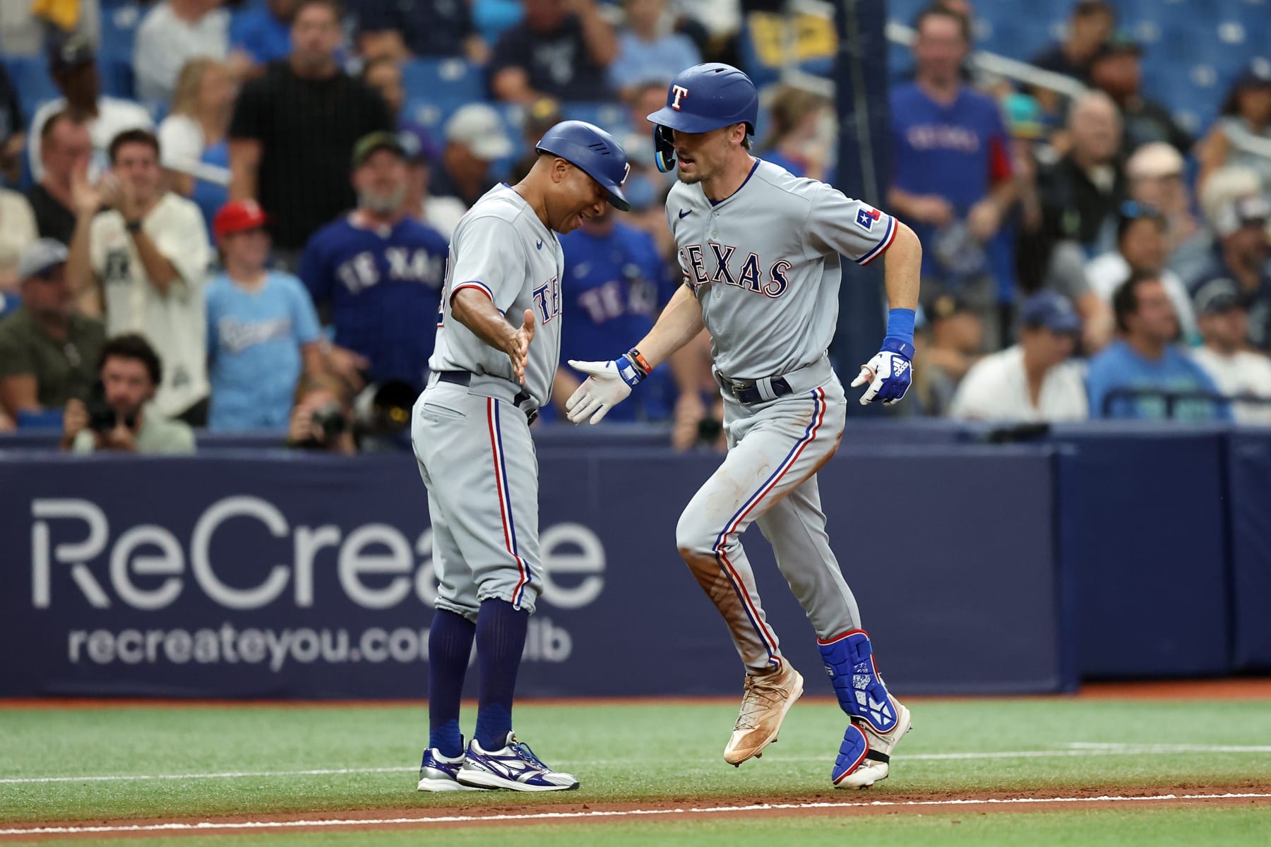 TAMPA, FL - OCTOBER 04: Evan Carter #32 of the Texas Rangers celebrates with third-base coach Tony Beasley #27 after hitting a home run in the fourth inning during Game 2 of the Wild Card Series between the Texas Rangers and the Tampa Bay Rays at Tropicana Field on Wednesday, October 4, 2023 in Tampa, Florida. (Photo by Mike Carlson/MLB Photos via Getty Images)