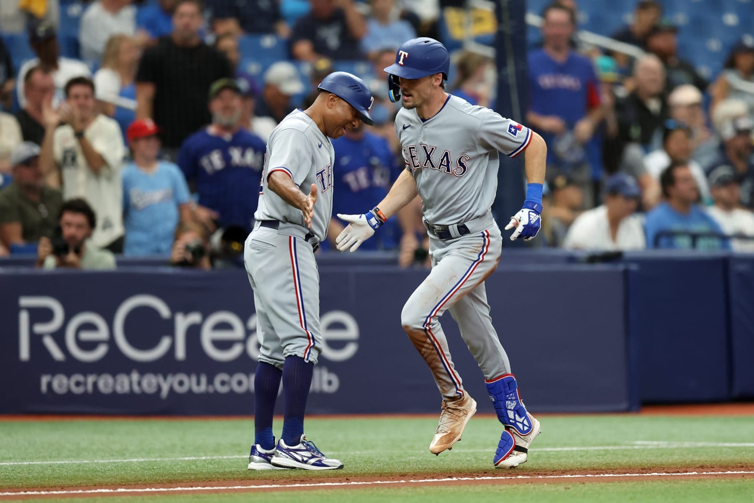 TAMPA, FL - OCTOBER 04: Evan Carter #32 of the Texas Rangers celebrates with third-base coach Tony Beasley #27 after hitting a home run in the fourth inning during Game 2 of the Wild Card Series between the Texas Rangers and the Tampa Bay Rays at Tropicana Field on Wednesday, October 4, 2023 in Tampa, Florida. (Photo by Mike Carlson/MLB Photos via Getty Images)