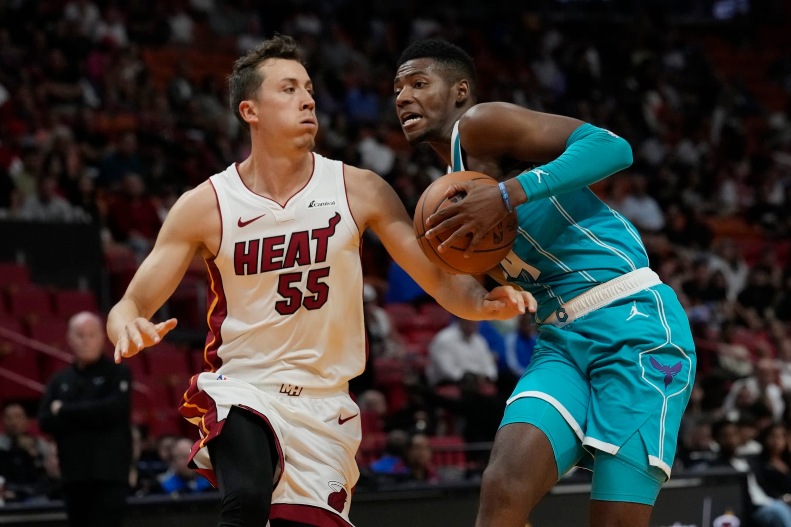 Miami Heat forward Duncan Robinson (55) defends Charlotte Hornets forward Brandon Miller during the first half of an NBA preseason basketball game, Tuesday, Oct. 10, 2023, in Miami. (AP Photo/Marta Lavandier)
