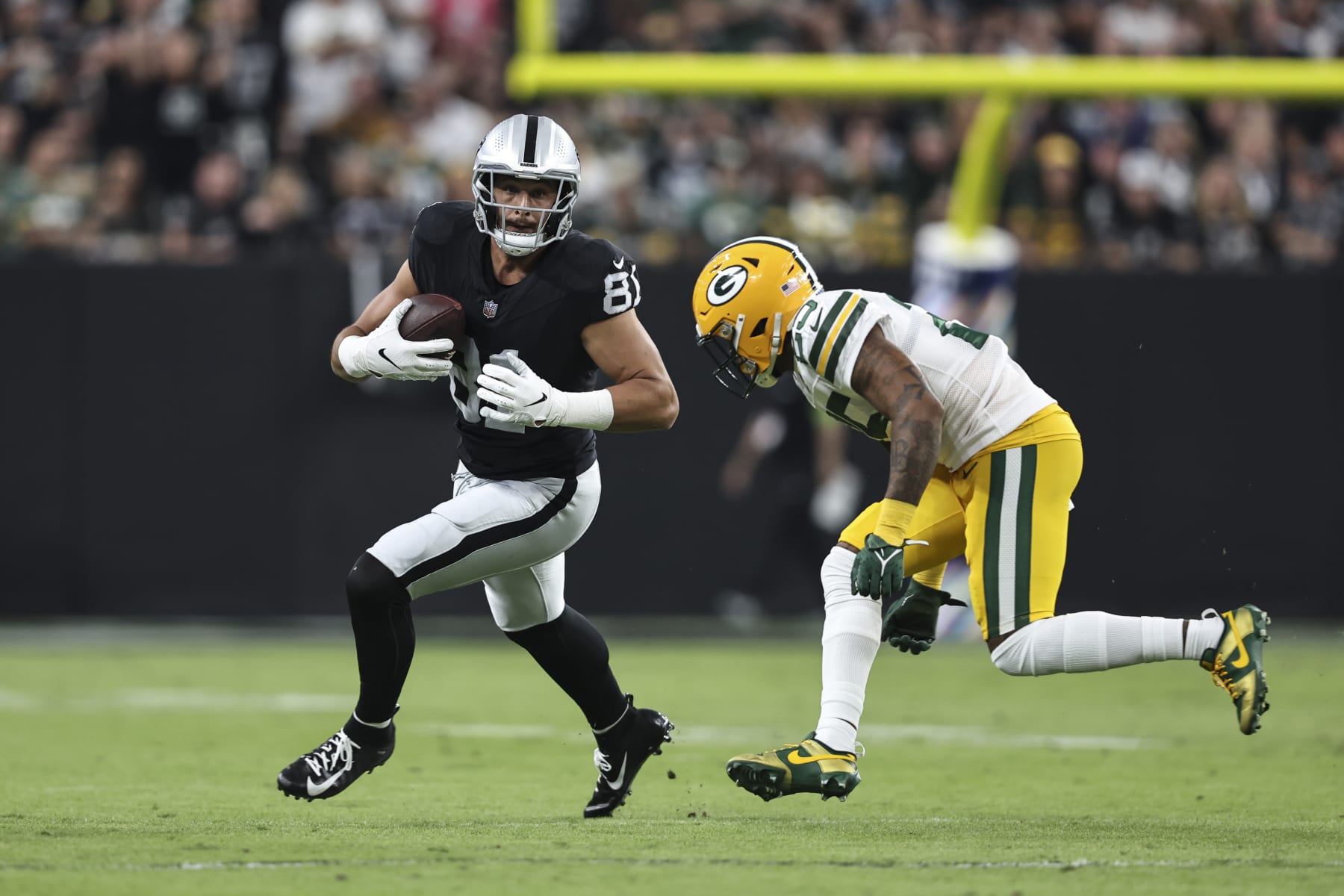 LAS VEGAS, NEVADA - OCTOBER 09: Austin Hooper #81 of the Las Vegas Raiders runs with the ball against Keisean Nixon #25 of the Green Bay Packers during an NFL football game between the Las Vegas Raiders and the Green Bay Packers at Allegiant Stadium on October 09, 2023 in Las Vegas, Nevada. (Photo by Michael Owens/Getty Images)