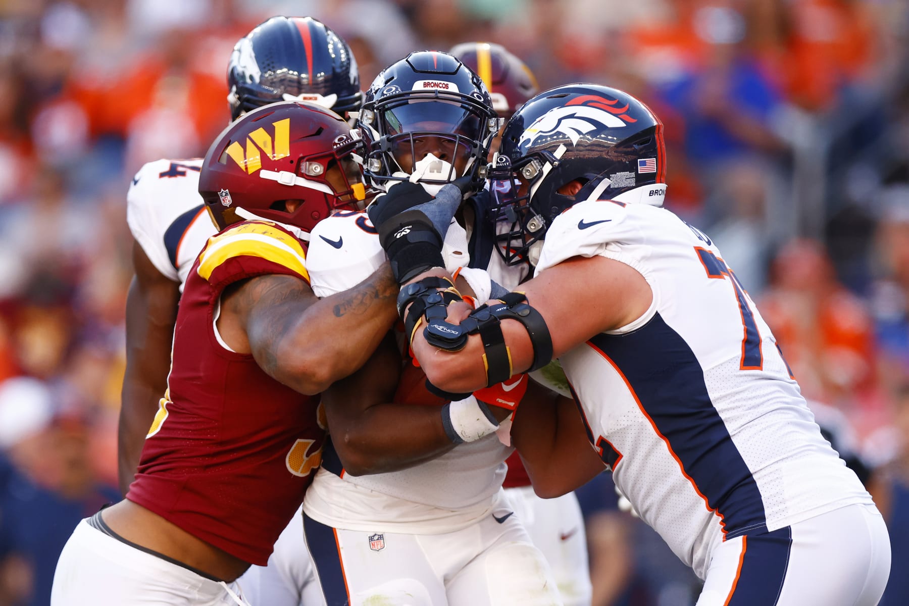 DENVER, COLORADO - SEPTEMBER 17: Montez Sweat #90 of the Washington Commanders attempts to tackle Javonte Williams #33 of the Denver Broncos while Garett Bolles #72 of the Denver Broncos pushes Williams for extra yards during the fourth quarter at Empower Field At Mile High on September 17, 2023 in Denver, Colorado. (Photo by Justin Edmonds/Getty Images)