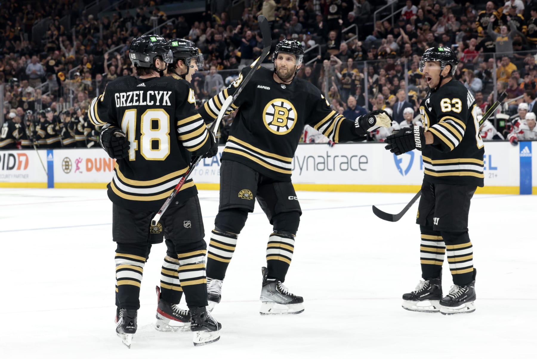 BOSTON, MA - OCTOBER 03: Boston Bruins left wing Brad Marchand (63) moves in to congratulate Boston Bruins center Matthew Poitras (51) during a game between the Boston Bruins and the Washington Capitals on October 3, 2023, at TD Garden in Boston, Massachusetts. (Photo by Fred Kfoury III/Icon Sportswire via Getty Images)