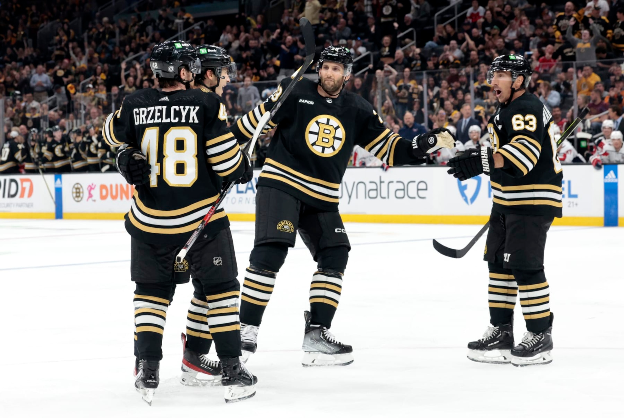 BOSTON, MA - OCTOBER 03: Boston Bruins left wing Brad Marchand (63) moves in to congratulate Boston Bruins center Matthew Poitras (51) during a game between the Boston Bruins and the Washington Capitals on October 3, 2023, at TD Garden in Boston, Massachusetts. (Photo by Fred Kfoury III/Icon Sportswire via Getty Images) BOSTON, MA - OCTOBER 03: Boston Bruins left wing Brad Marchand (63) moves in to congratulate Boston Bruins center Matthew Poitras (51) during a game between the Boston Bruins and the Washington Capitals on October 3, 2023, at TD Garden in Boston, Massachusetts. (Photo by Fred Kfoury III/Icon Sportswire via Getty Images)