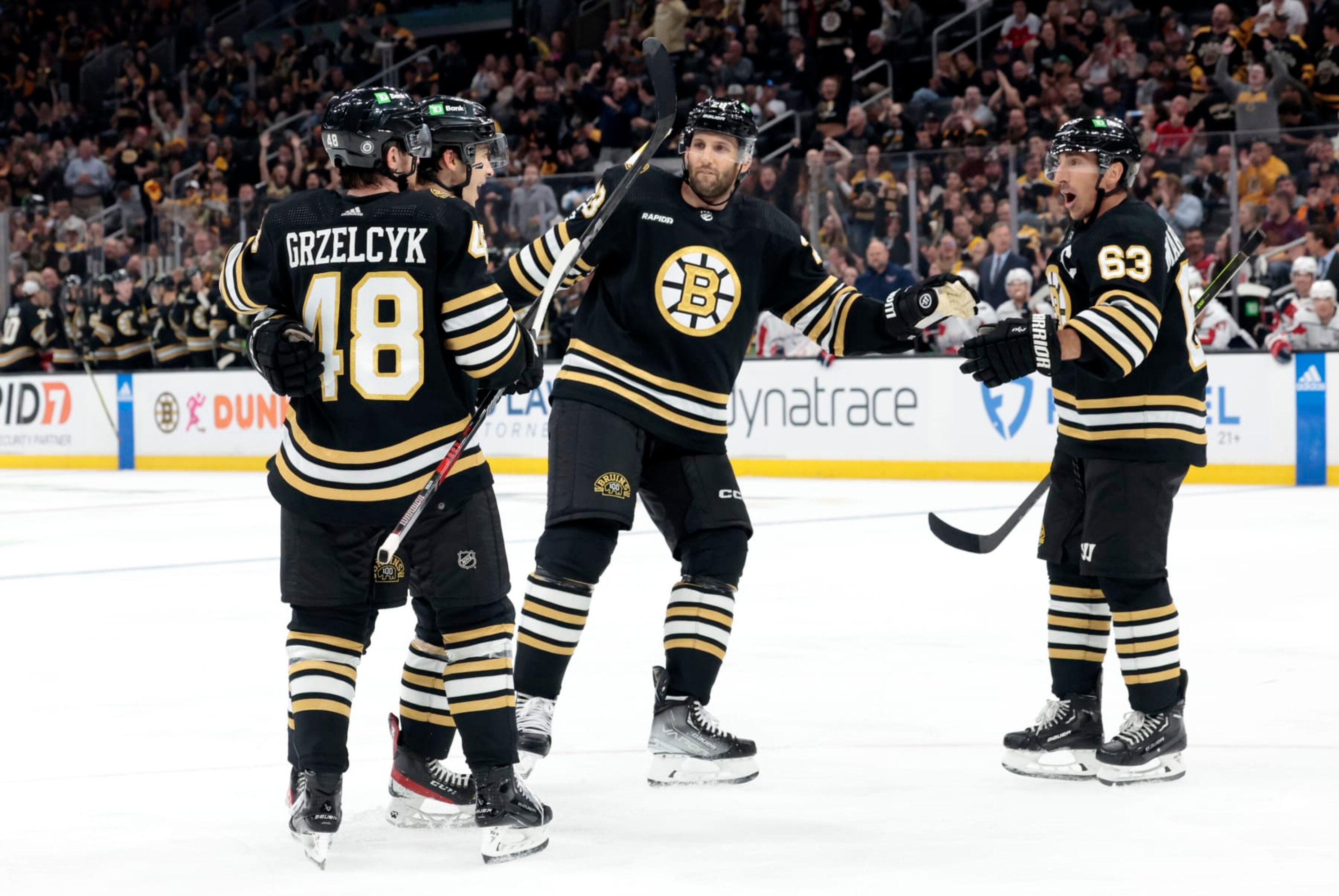 BOSTON, MA - OCTOBER 03: Boston Bruins left wing Brad Marchand (63) moves in to congratulate Boston Bruins center Matthew Poitras (51) during a game between the Boston Bruins and the Washington Capitals on October 3, 2023, at TD Garden in Boston, Massachusetts. (Photo by Fred Kfoury III/Icon Sportswire via Getty Images)