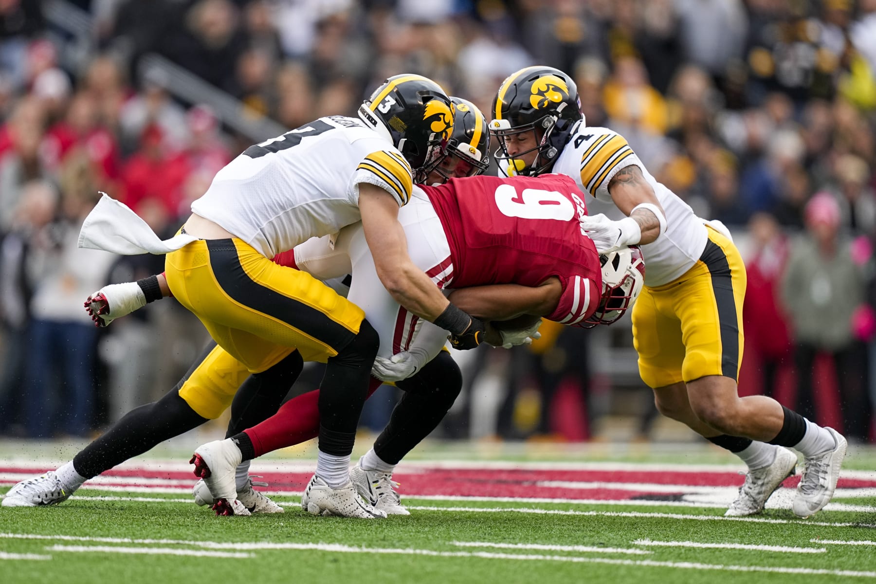 Iowa defensive backs Cooper DeJean (3), Xavier Nwankpa, center top, and Koen Entringer (4) tackle Wisconsin wide receiver Bryson Green (9) during the first half of an NCAA college football game Saturday, Oct. 14, 2023, in Madison, Wis. (AP Photo/Andy Manis)