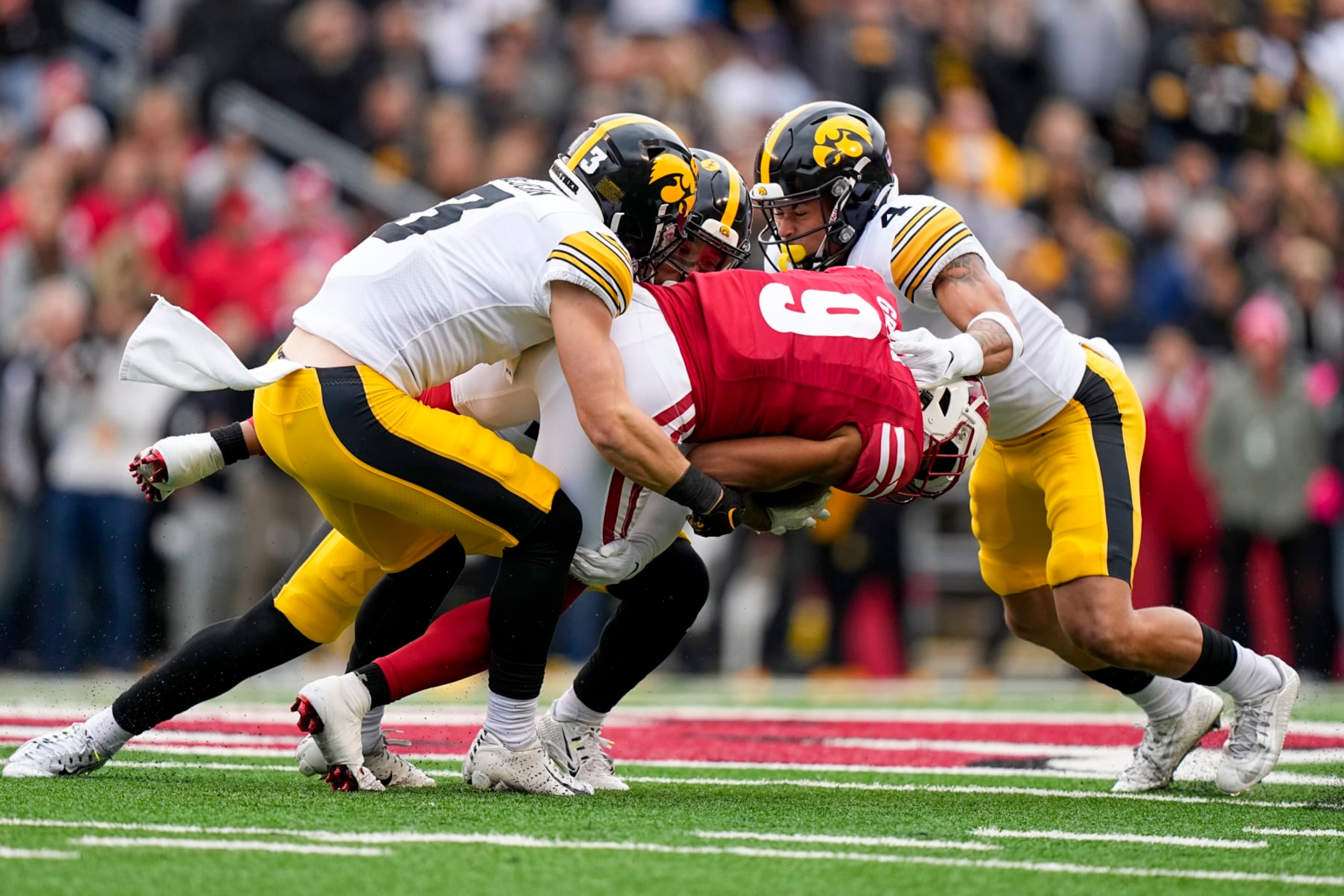 Iowa defensive backs Cooper DeJean (3), Xavier Nwankpa, center top, and Koen Entringer (4) tackle Wisconsin wide receiver Bryson Green (9) during the first half of an NCAA college football game Saturday, Oct. 14, 2023, in Madison, Wis. (AP Photo/Andy Manis)