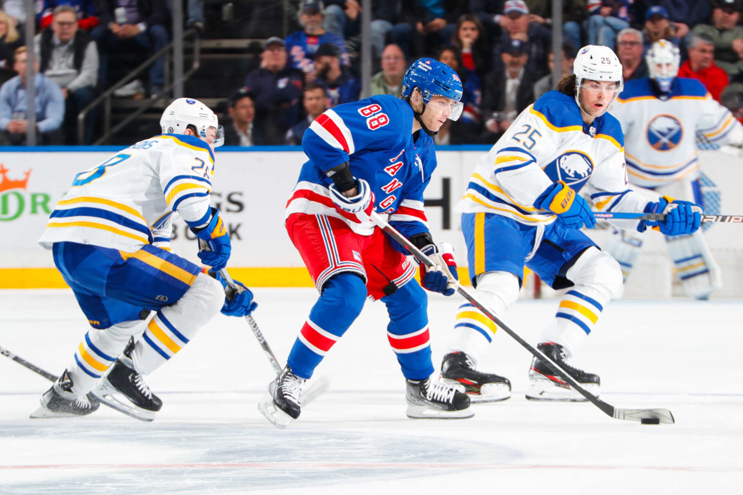 NEW YORK, NEW YORK - APRIL 10:  Patrick Kane #88 of the New York Rangers skates with the puck against Zemgus Girgensons #28 and Owen Power #25 of the Buffalo Sabres at Madison Square Garden on April 10, 2023 in New York City. (Photo by Jared Silber/NHLI via Getty Images)