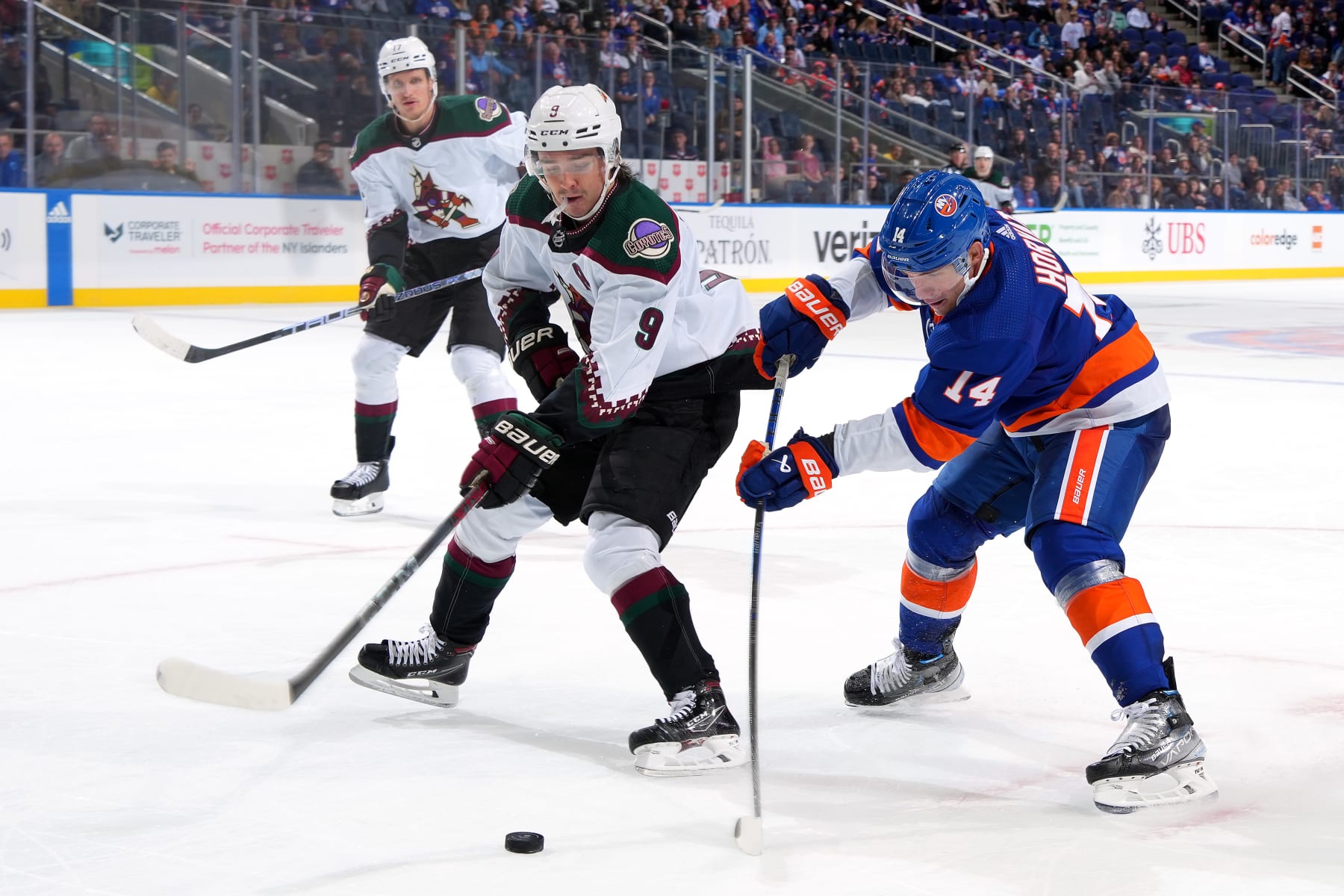 ELMONT, NEW YORK - OCTOBER 17:  Bo Horvat #14 of the New York Islanders is defended by Clayton Keller #9 of the Arizona Coyotes during the third period at UBS Arena on October 17, 2023 in Elmont, New York. (Photo by Mike Stobe/NHLI via Getty Images)
