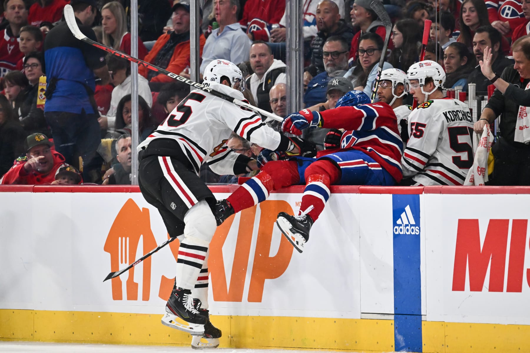 MONTREAL, CANADA - OCTOBER 14:  Jarred Tinordi #25 of the Chicago Blackhawks pushes Kirby Dach #77 of the Montreal Canadiens into the Blackhawks bench during the first period at the Bell Centre on October 14, 2023 in Montreal, Quebec, Canada.  (Photo by Minas Panagiotakis/Getty Images)