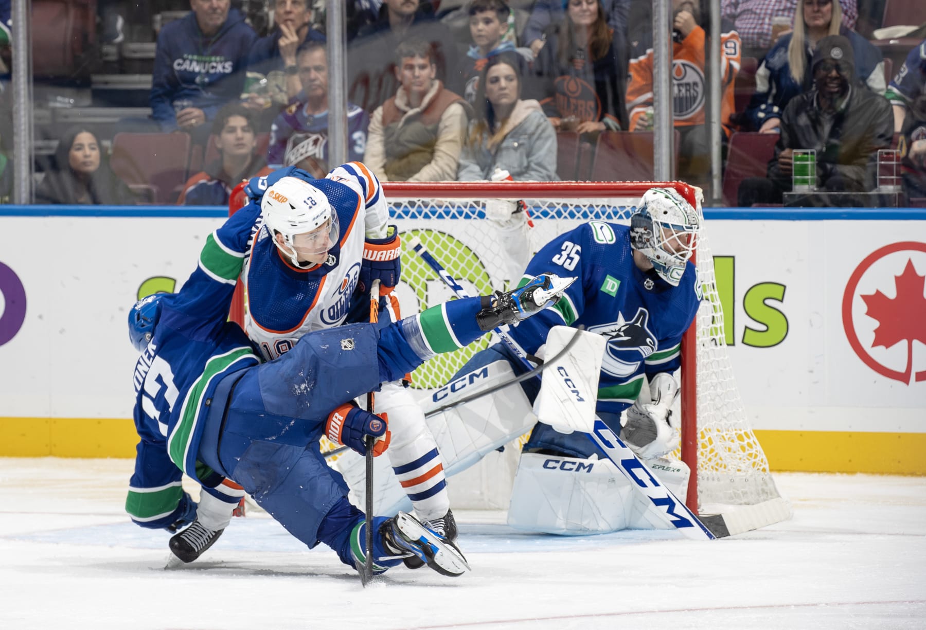 VANCOUVER, CANADA - OCTOBER 11: Zach Hyman #18 of the Edmonton Oilers checks Filip Hronek #17 of the Vancouver Canucks during the second period of their NHL game at Rogers Arena October 11, 2023 in Vancouver, British Columbia, Canada.  (Photo by Jeff Vinnick/NHLI via Getty Images)