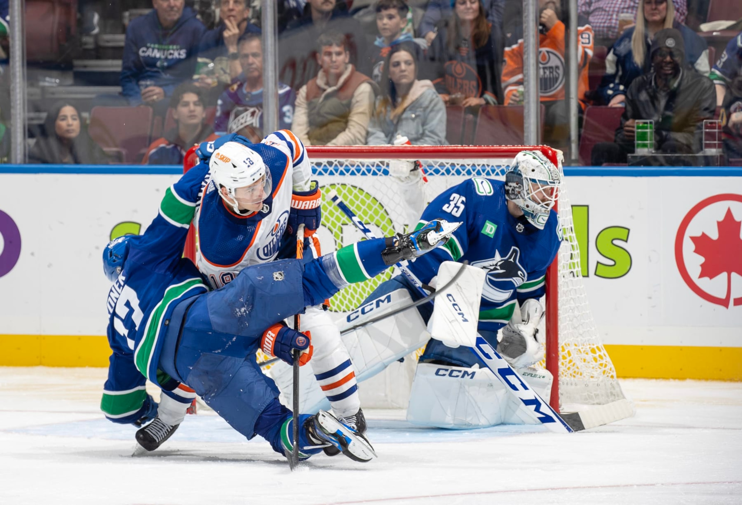 VANCOUVER, CANADA - OCTOBER 11: Zach Hyman #18 of the Edmonton Oilers checks Filip Hronek #17 of the Vancouver Canucks during the second period of their NHL game at Rogers Arena October 11, 2023 in Vancouver, British Columbia, Canada.  (Photo by Jeff Vinnick/NHLI via Getty Images)