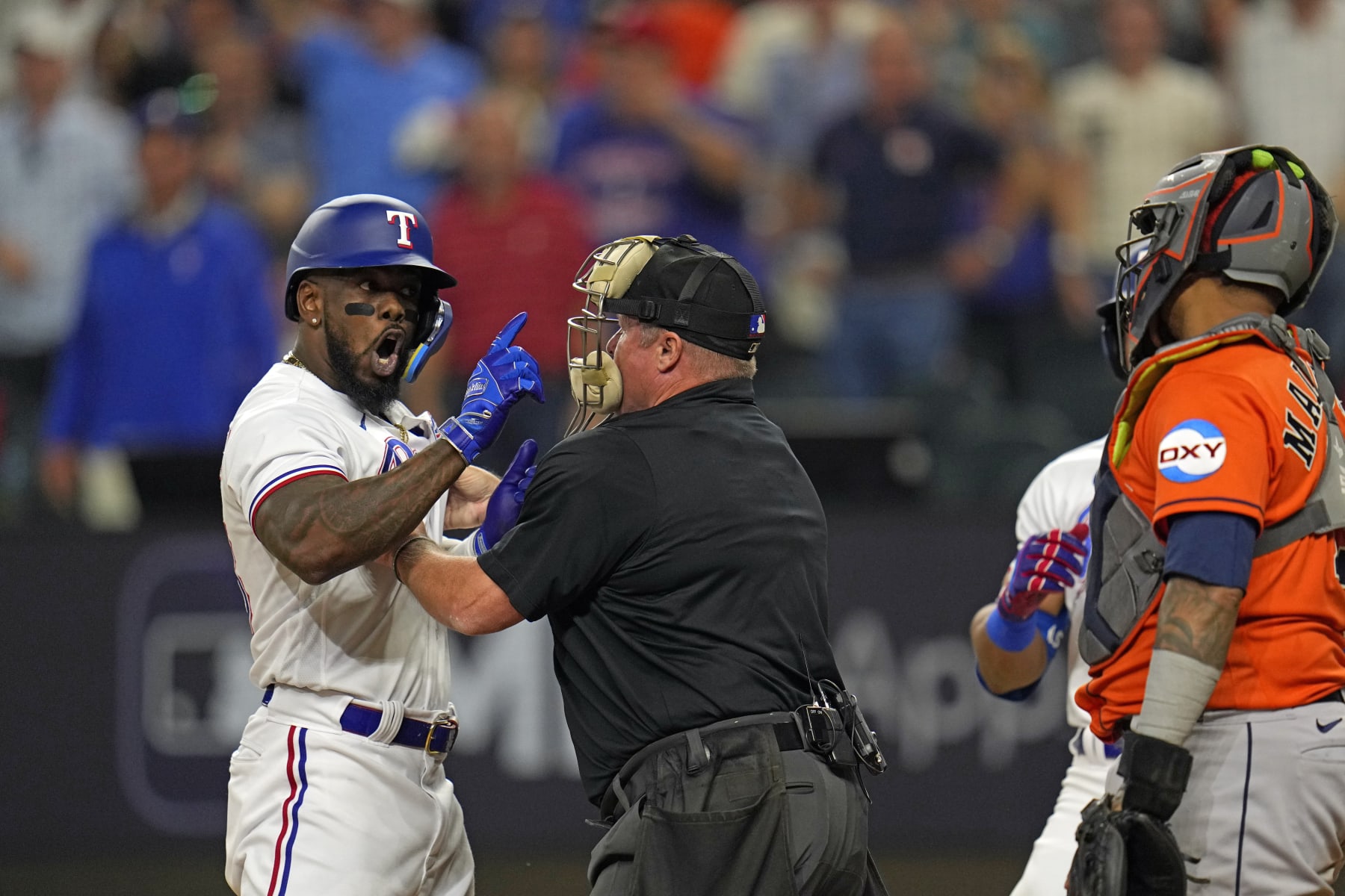 Home Plate umpire Marvin Hudson, center, restrains Texas Rangers' Adolis Garcia, left, as he yells at Houston Astros catcher Martin Maldonado after being hit by a pitch during the eighth inning in Game 5 of the baseball American League Championship Series Friday, Oct. 20, 2023, in Arlington, Texas. (AP Photo/Julio Cortez) Home Plate umpire Marvin Hudson, center, restrains Texas Rangers' Adolis Garcia, left, as he yells at Houston Astros catcher Martin Maldonado after being hit by a pitch during the eighth inning in Game 5 of the baseball American League Championship Series Friday, Oct. 20, 2023, in Arlington, Texas. (AP Photo/Julio Cortez)