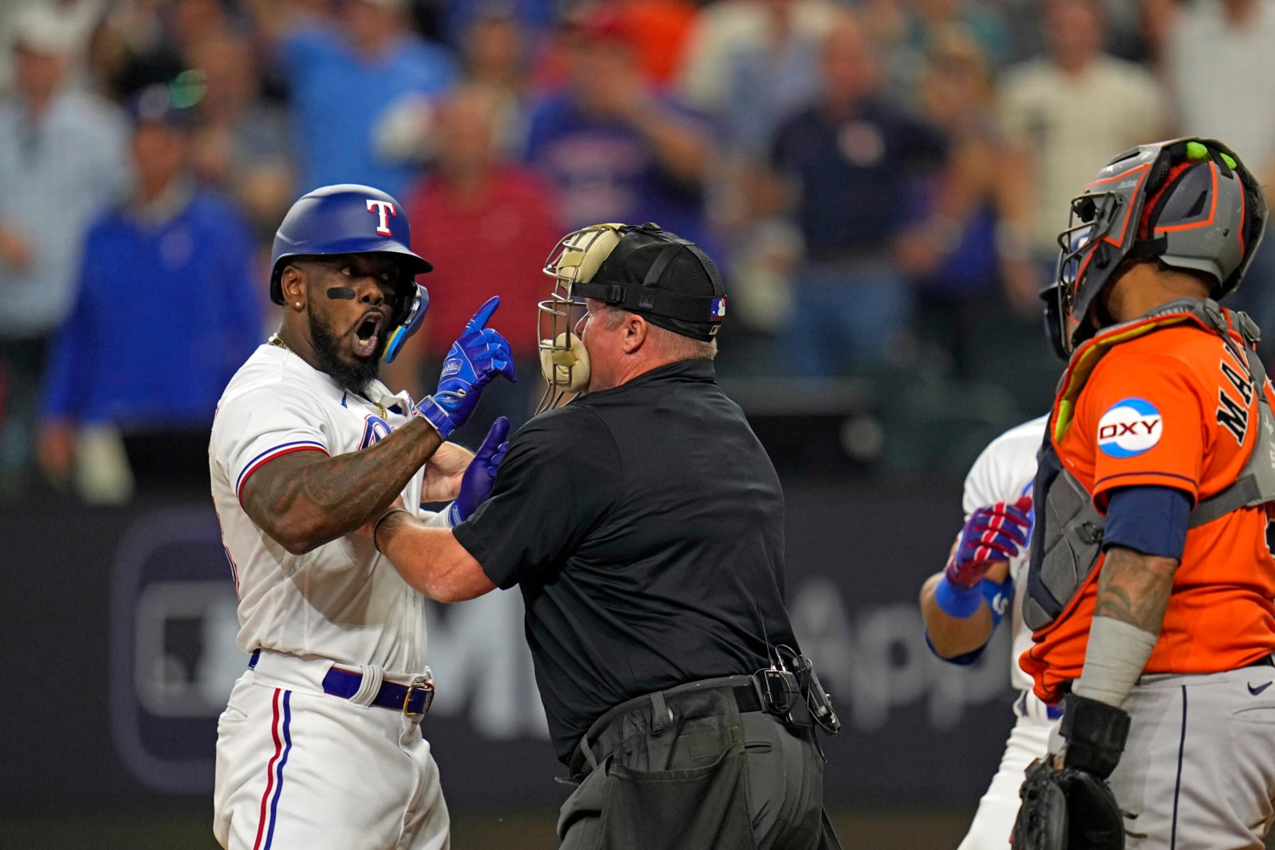 Home Plate umpire Marvin Hudson, center, restrains Texas Rangers' Adolis Garcia, left, as he yells at Houston Astros catcher Martin Maldonado after being hit by a pitch during the eighth inning in Game 5 of the baseball American League Championship Series Friday, Oct. 20, 2023, in Arlington, Texas. (AP Photo/Julio Cortez)