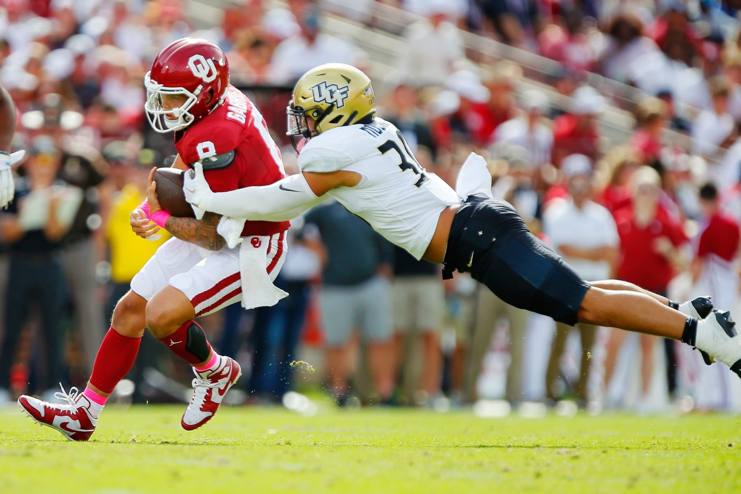 NORMAN, OKLAHOMA - OCTOBER 21:  Quarterback Dillon Gabriel #8 of the Oklahoma Sooners protects the ball as linebacker Kam Moore #30 of the UCF Knights dives for a tackle in the first quarter at Gaylord Family Oklahoma Memorial Stadium on October 21, 2023 in Norman, Oklahoma.  (Photo by Brian Bahr/Getty Images)