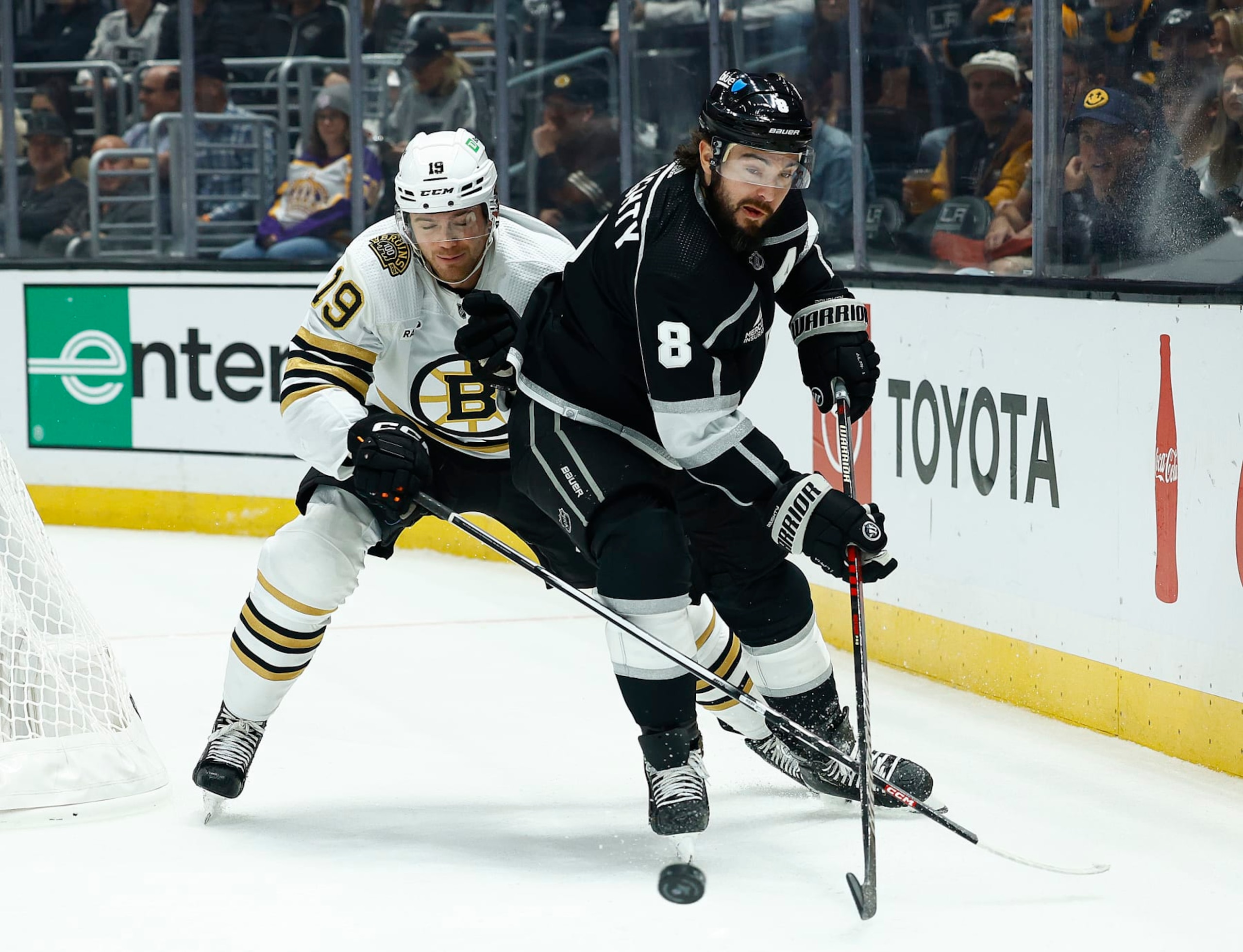 LOS ANGELES, CALIFORNIA - OCTOBER 21: Drew Doughty #8 of the Los Angeles Kings skates the puck against Johnny Beecher #19 of the Boston Bruins in the first period at Crypto.com Arena on October 21, 2023 in Los Angeles, California. (Photo by Ronald Martinez/Getty Images)