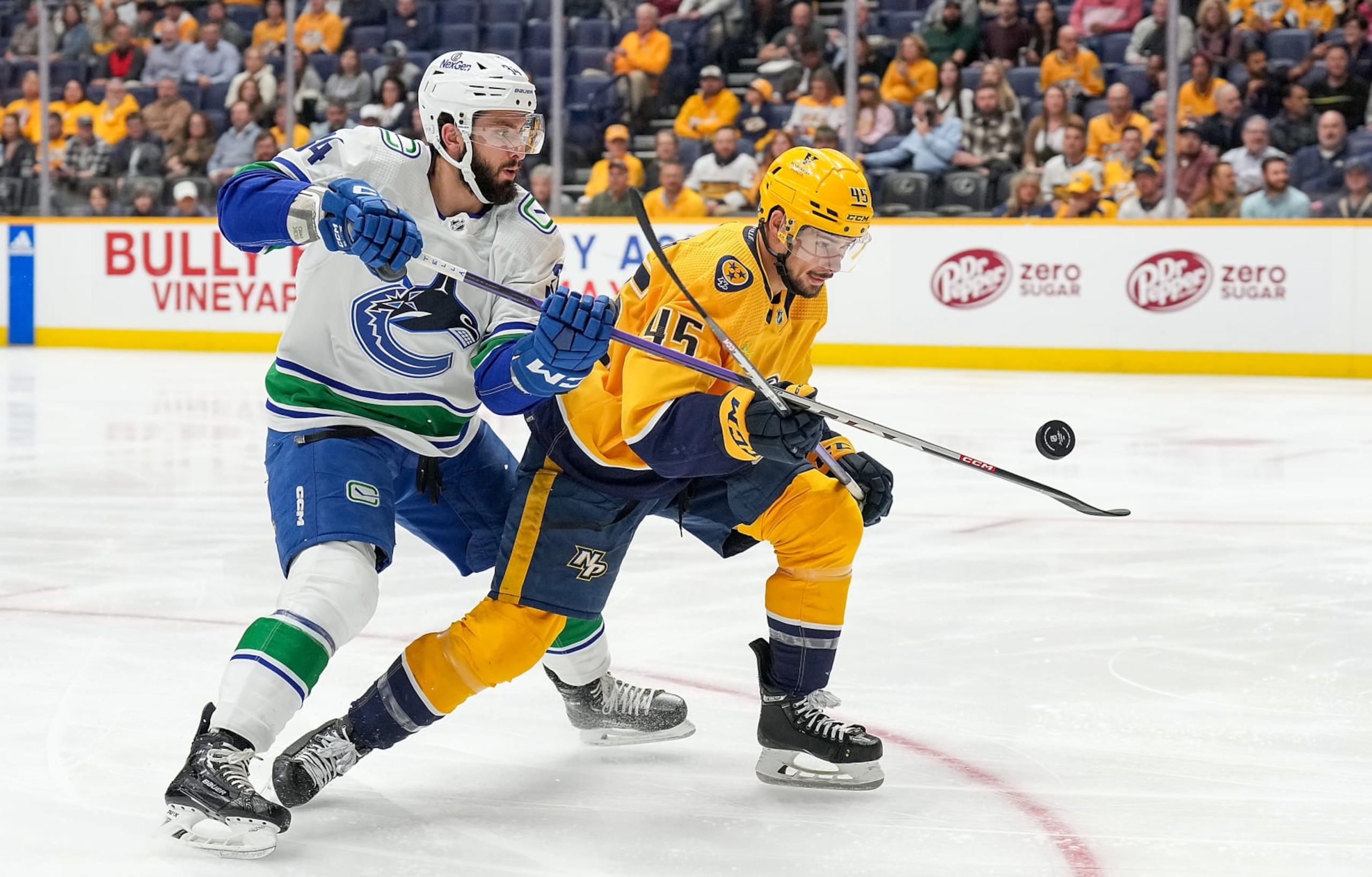 NASHVILLE, TENNESSEE - OCTOBER 24: Alexandre Carrier #45 of the Nashville Predators defends against Phillip Di Giuseppe #34 of the Vancouver Canucks during an NHL game at Bridgestone Arena on October 24, 2023 in Nashville, Tennessee. (Photo by John Russell/NHLI via Getty Images)