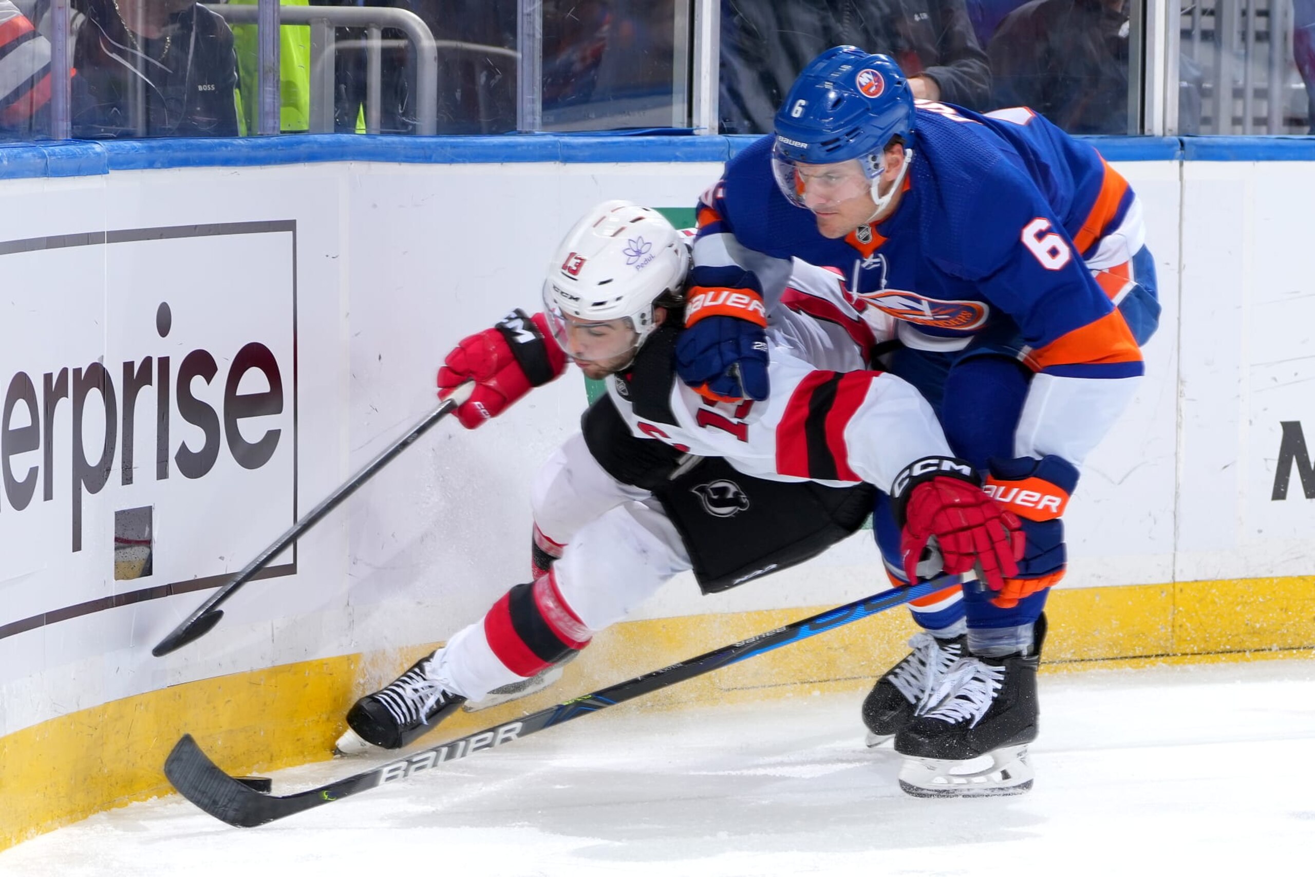 ELMONT, NEW YORK - OCTOBER 20:  Nico Hischier #13 of the New Jersey Devils is checked by Ryan Pulock #6 of the New York Islanders during the second period at UBS Arena on October 20, 2023 in Elmont, New York. (Photo by Mike Stobe/NHLI via Getty Images)