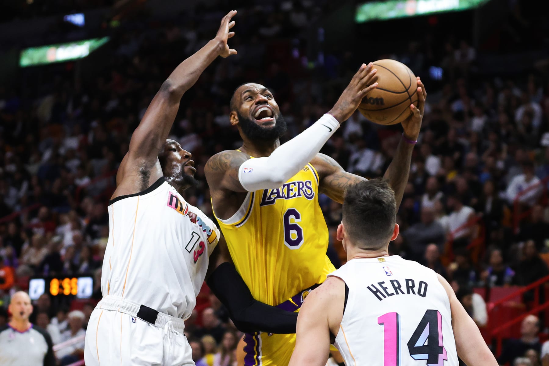 MIAMI, FLORIDA - DECEMBER 28: LeBron James #6 of the Los Angeles Lakers goes to the basket against Bam Adebayo #13 and Tyler Herro #14 of the Miami Heat during the fourth quarter of the game at FTX Arena on December 28, 2022 in Miami, Florida. NOTE TO USER: User expressly acknowledges and agrees that, by downloading and or using this photograph, User is consenting to the terms and conditions of the Getty Images License Agreement. (Photo by Megan Briggs/Getty Images)